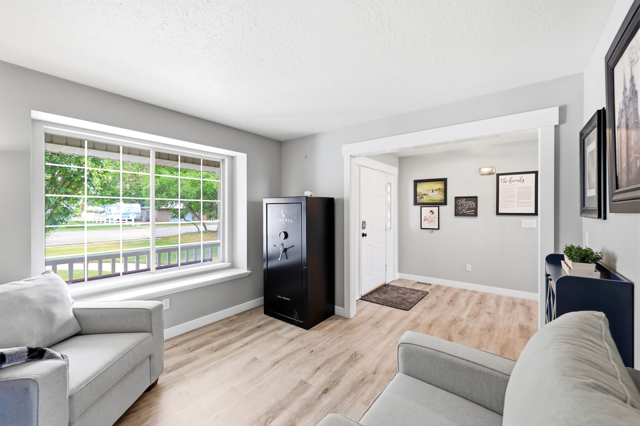 Spacious room with light wood-finish flooring, a large window featuring white grid panes, and a crisp white trim package