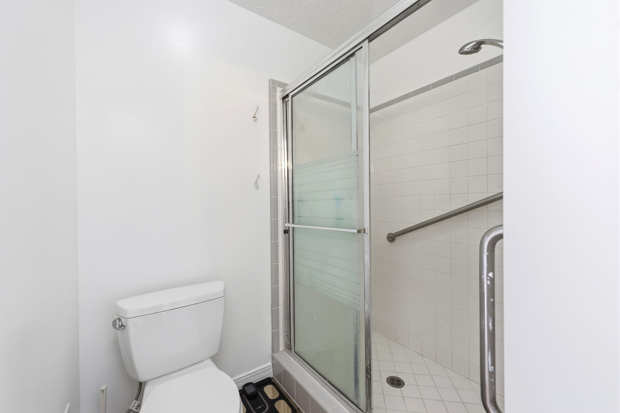 Shower with a sliding glass door, white subway tile surround, and a metal grab bar