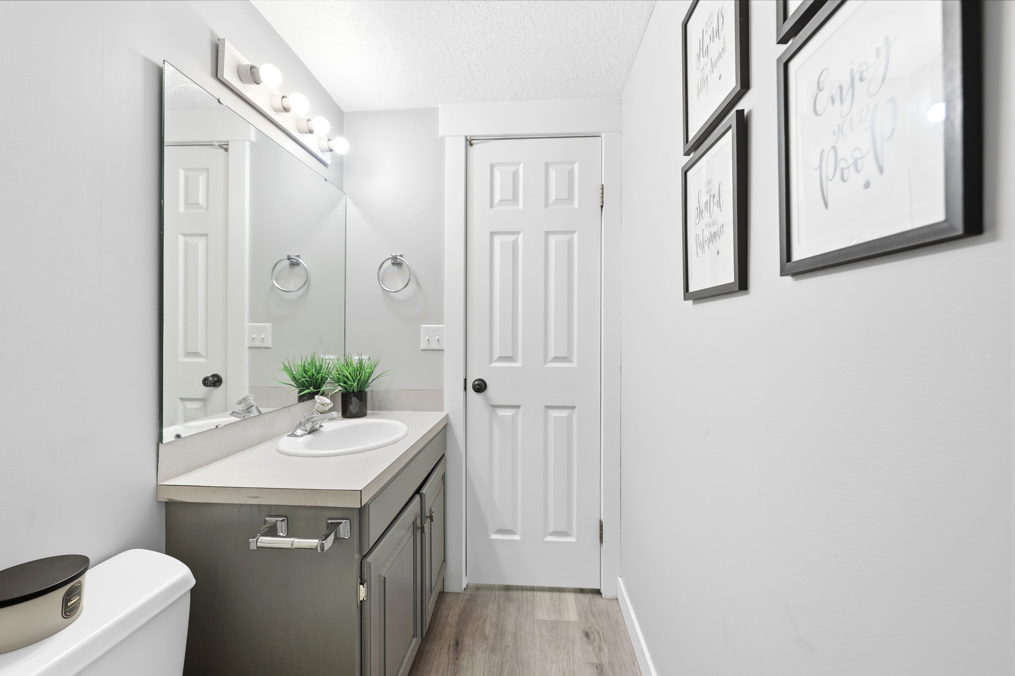 Bathroom featuring a built-in vanity with a single basin sink and gray cabinetry, a wide mirror, and an overhead light fixture