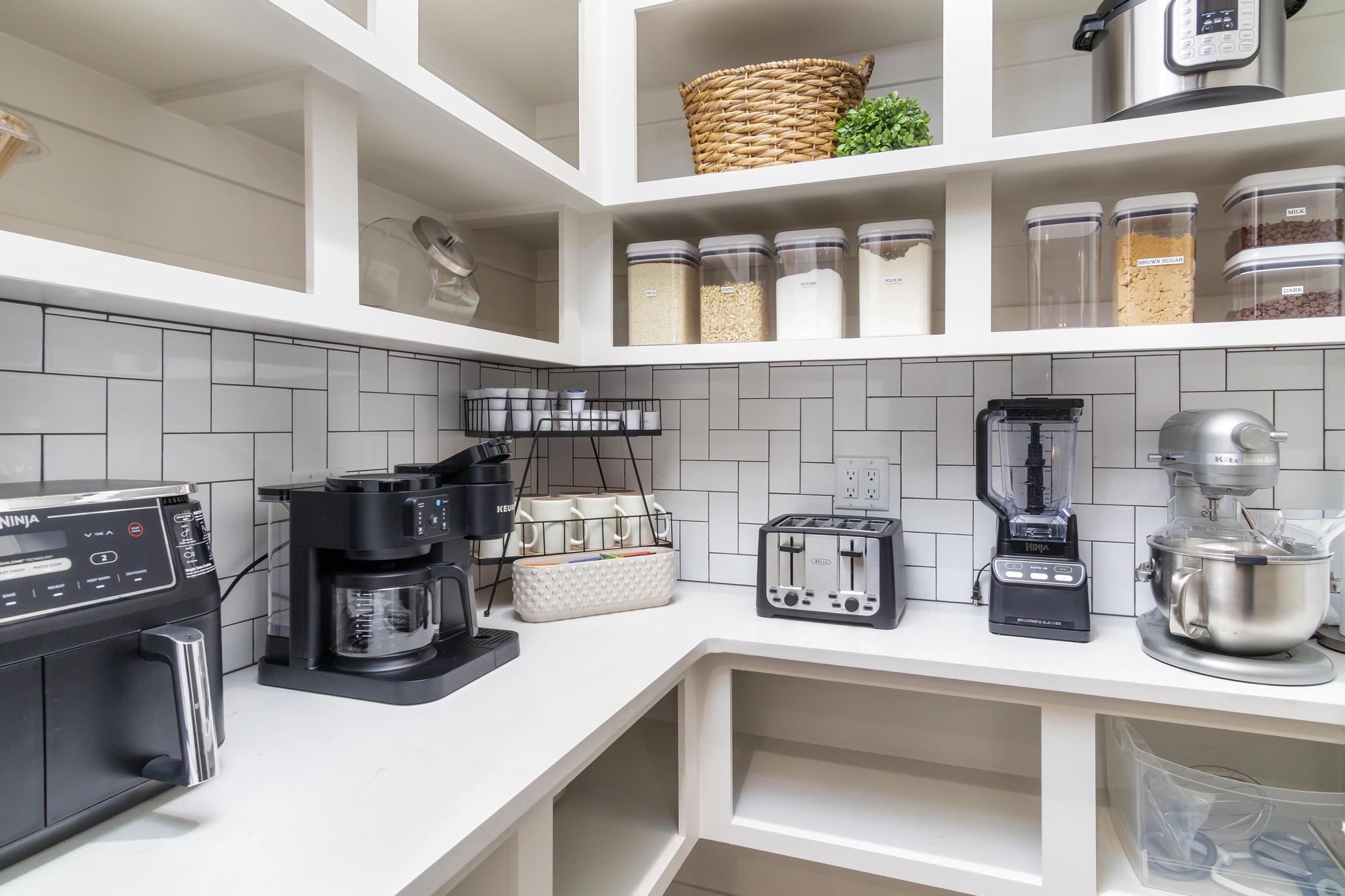 Pantry featuring built-in shelving, extensive counter space, subway tile backsplash, and integrated power outlets