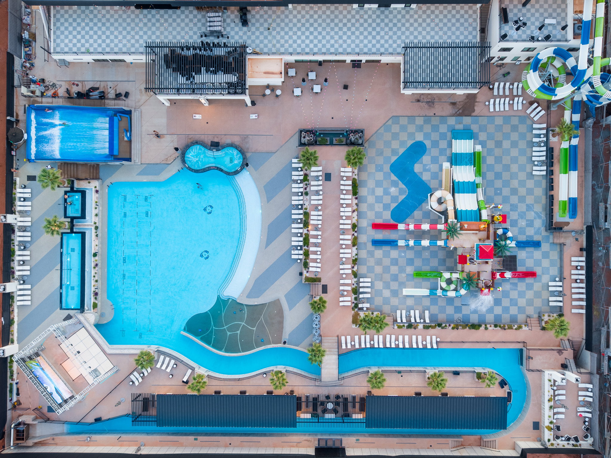 Expansive aquatic amenity featuring multiple pools, a winding lazy river, integrated water slides, and extensive lounge seating areas