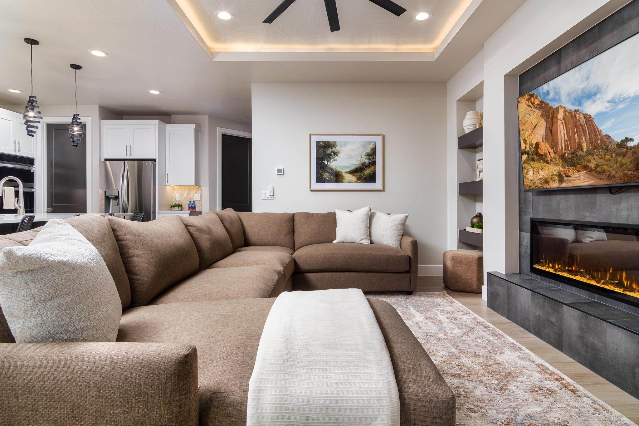 Spacious living area featuring a built-in electric fireplace with stone-look tile surround, recessed lighting, and a tray ceiling