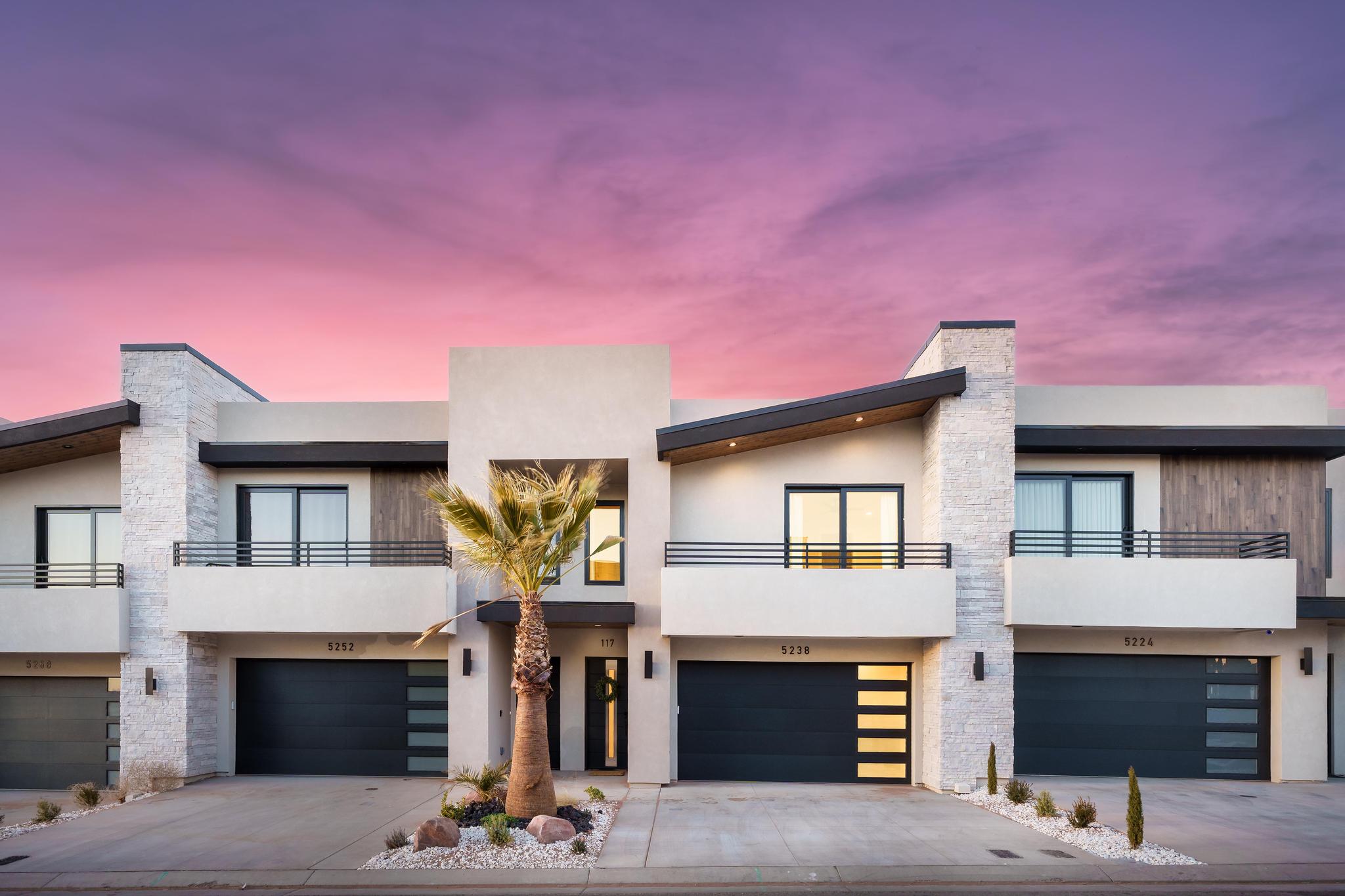 Contemporary architecture with stucco exteriors, stone accents, and dark frame windows