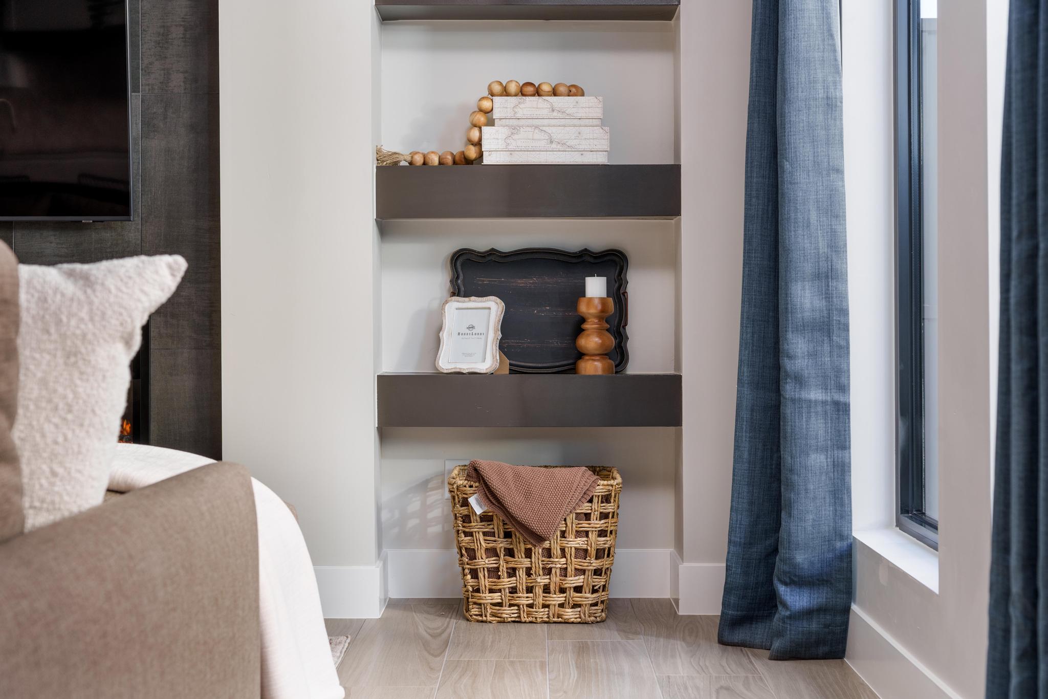 Built-in shelving unit with three dark wood-finish shelves, light wood-finish flooring, and a large window with floor-length blue drapery
