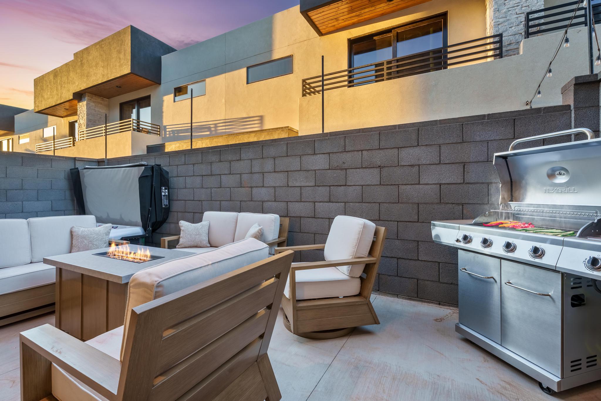 Outdoor patio featuring a built-in fire pit table, concrete block retaining wall, and a built-in hot tub