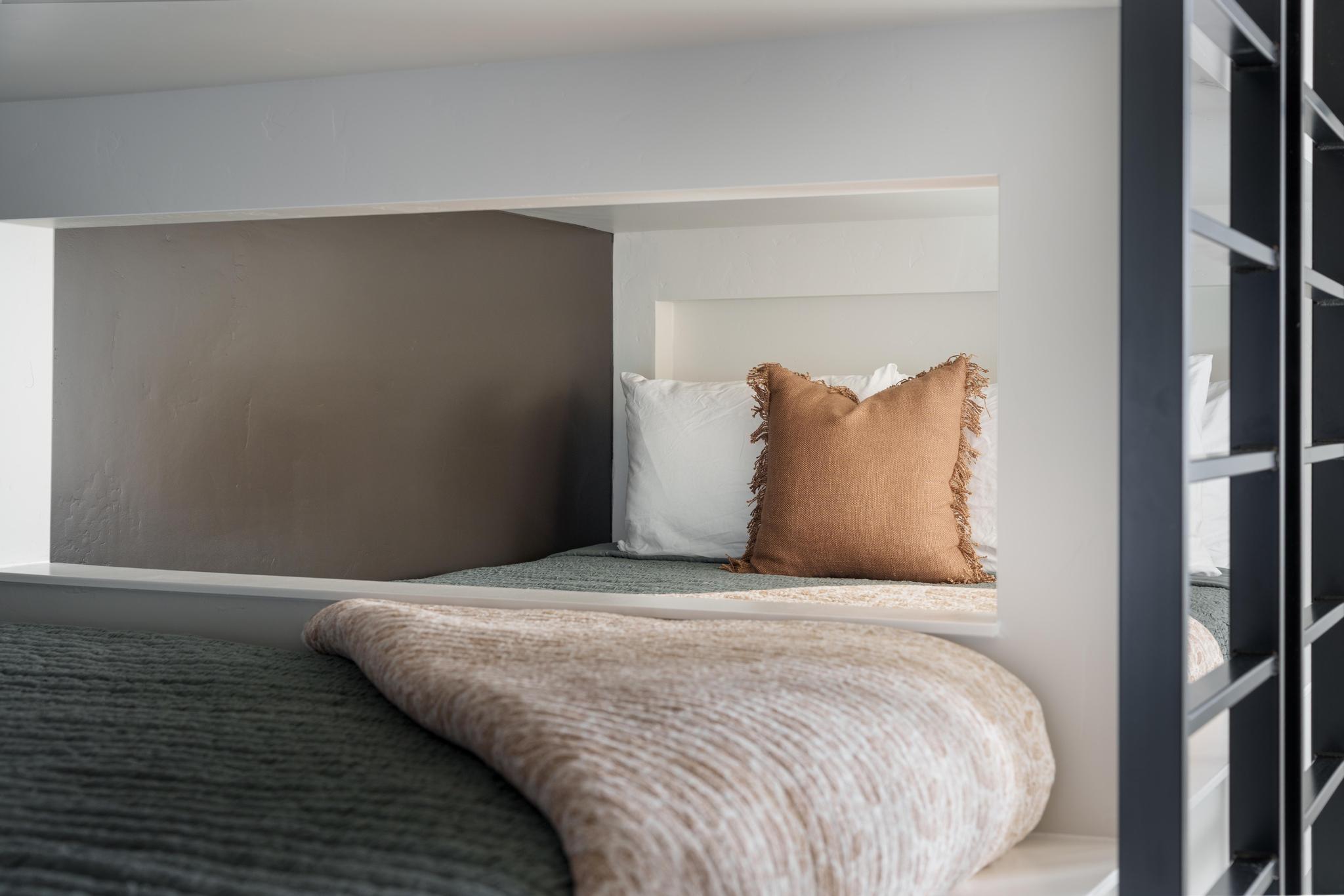 Built-in sleeping nook with neutral wall tones and a distinct metal railing