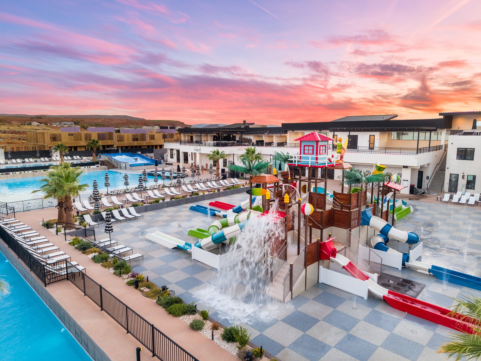 Expansive aquatic recreation area featuring multiple pools, a wave pool, and a multi-level water play structure with slides and water features