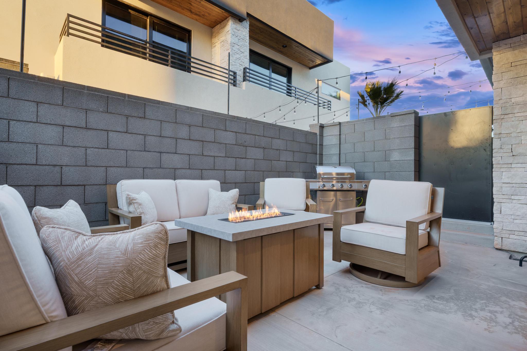 Outdoor patio featuring a concrete surface, built-in fire pit, string lighting, and a stainless steel grill