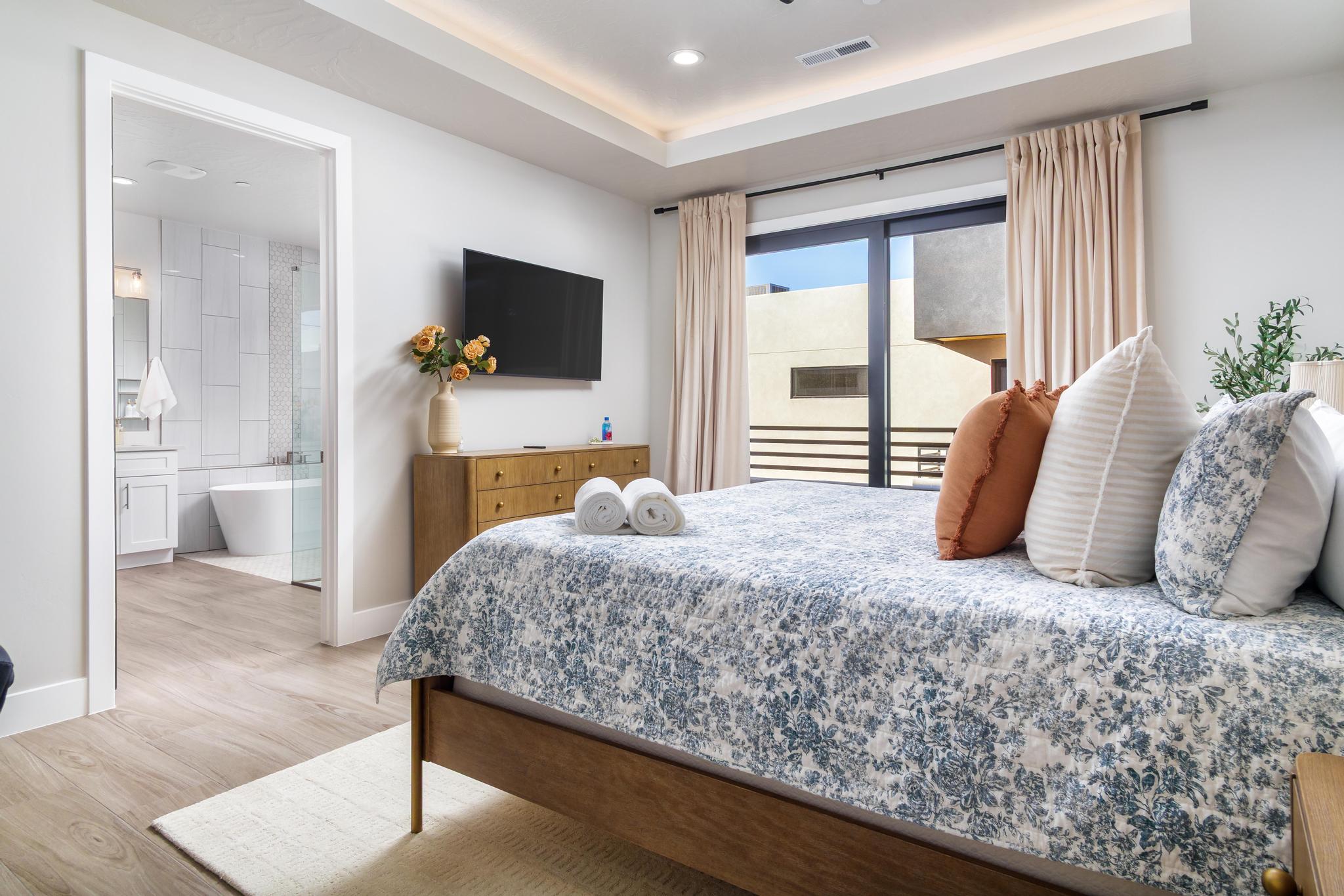 Bedroom featuring a tray ceiling with recessed lighting, wood-finish flooring, and a glass sliding door
