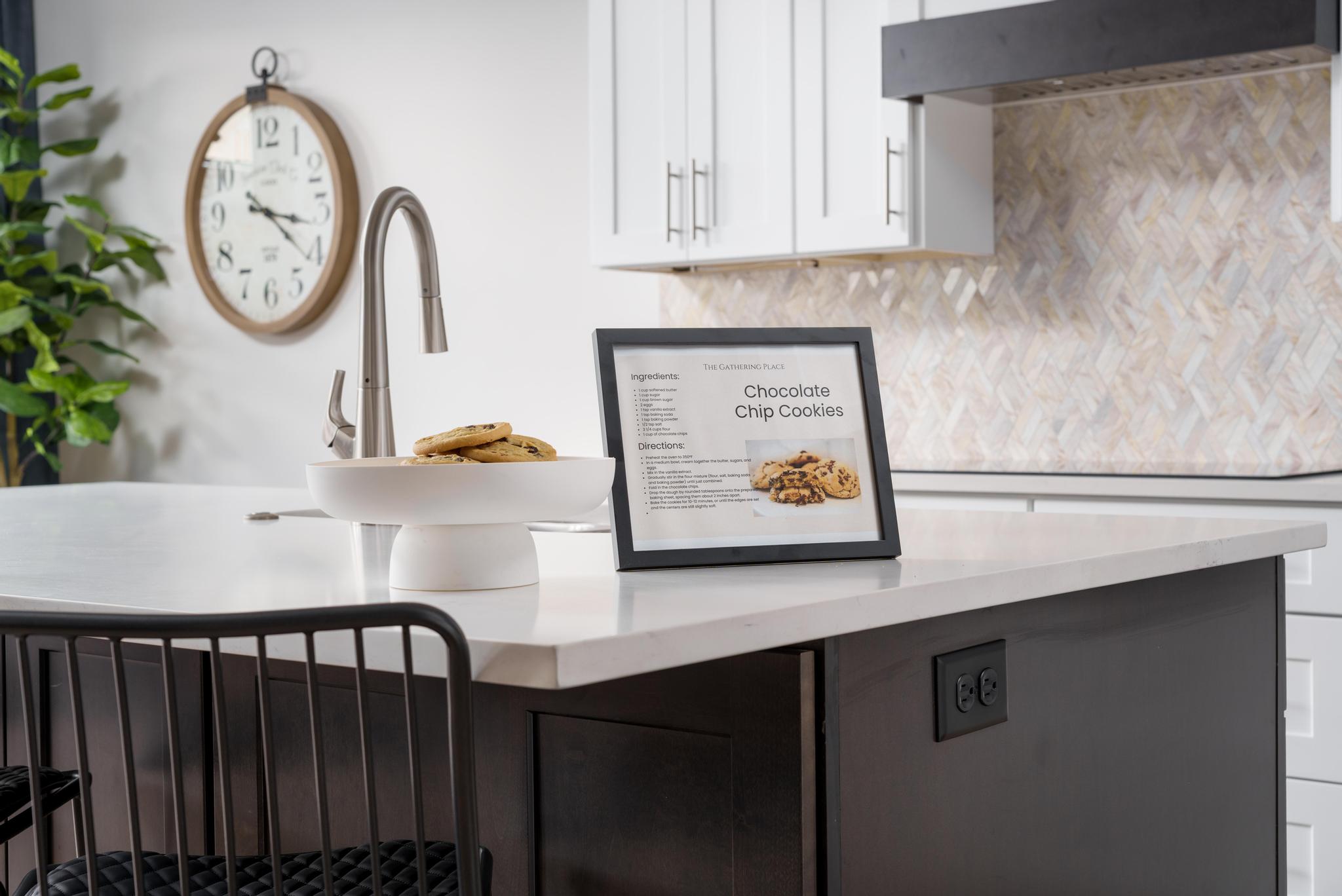 Kitchen island with a white countertop and dark cabinetry, featuring an integrated sink with a stainless steel faucet