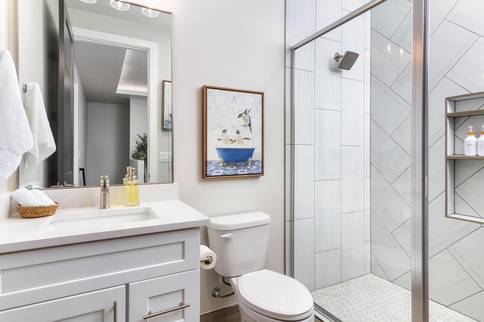 Bathroom featuring a white vanity with an undermount sink, a framed mirror, and a glass-enclosed shower