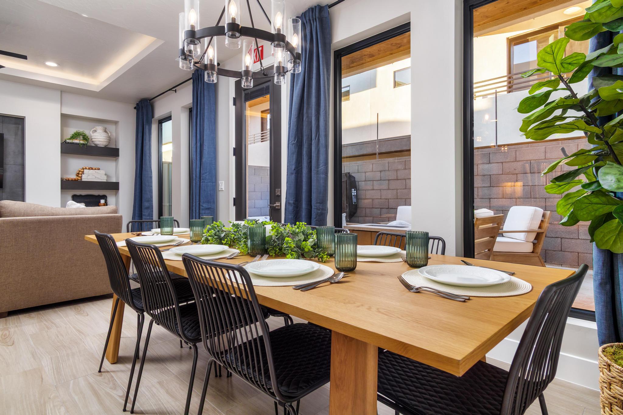 Dining space featuring a wood-finish table, a modern chandelier with cylindrical glass shades, and light wood-finish flooring