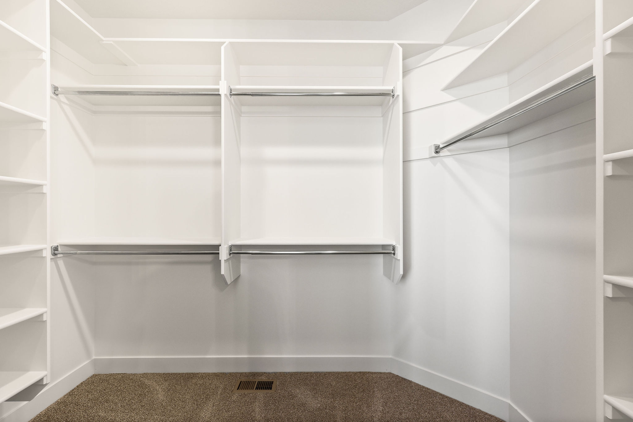 Custom closet system featuring white shelving and chrome hanging rods