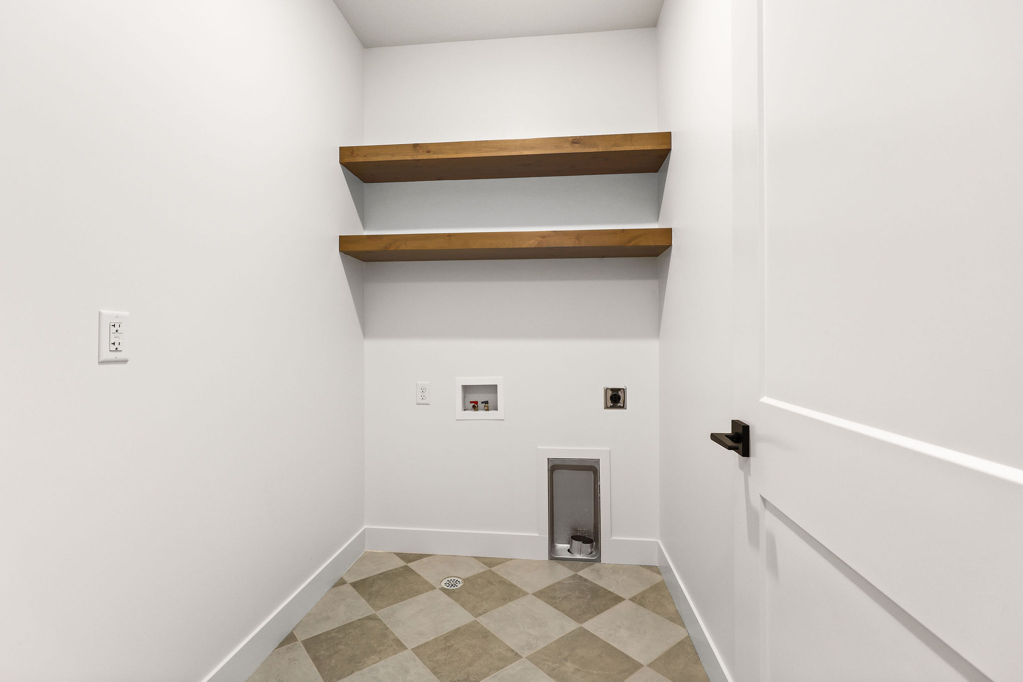 Dedicated utility space featuring two wood-finish floating shelves, a checkerboard-patterned floor, and white trim