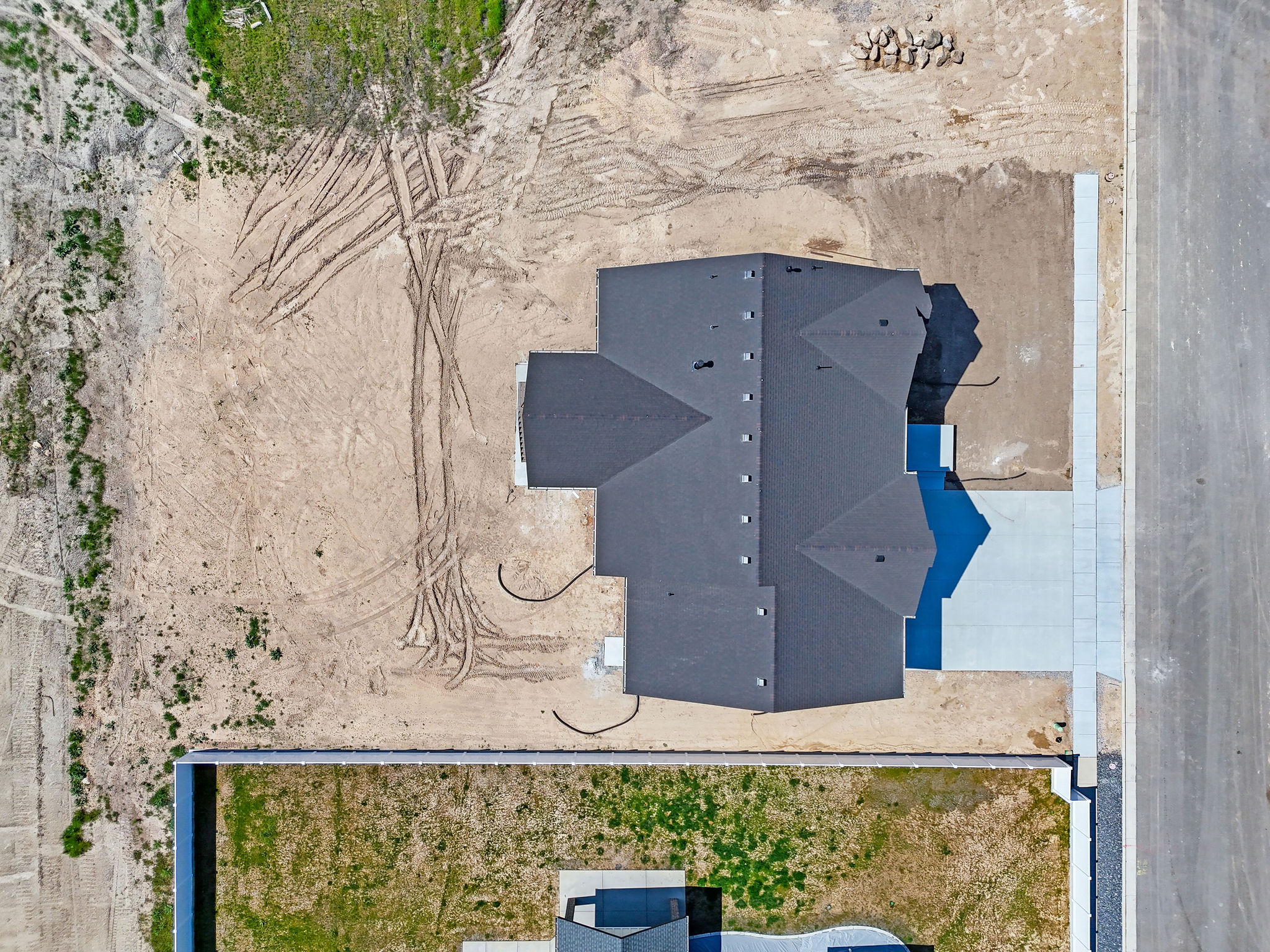 New construction residence featuring a dark shingle roof and a concrete driveway
