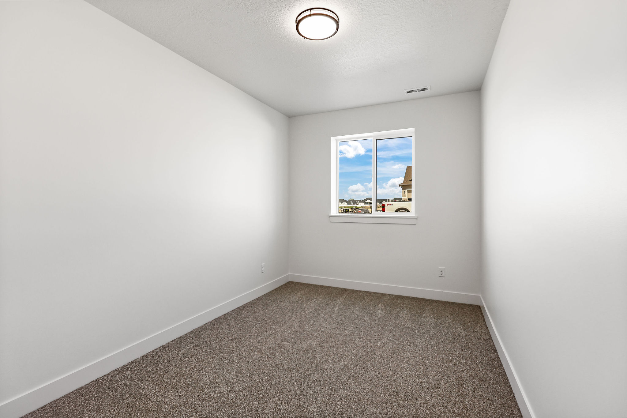 Neutral interior room featuring white walls, a single window, and a flush-mount ceiling light