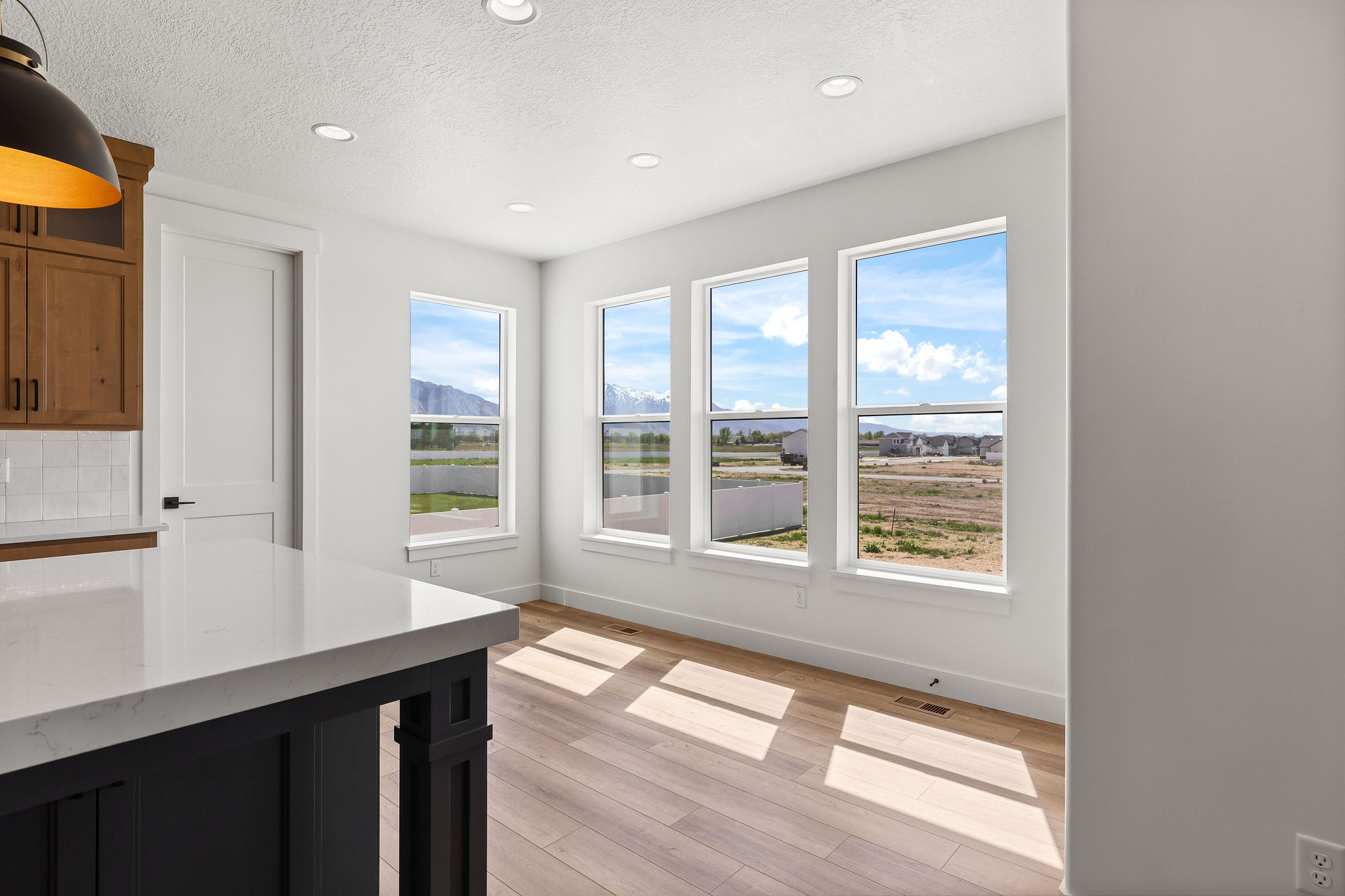 Open-concept dining space with four large windows and light wood-finish flooring