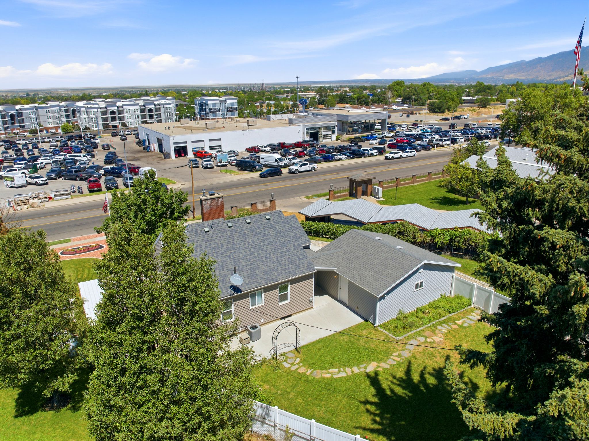 Aerial perspective highlighting the property with a gray shingle roof, light gray siding, and a detached garage