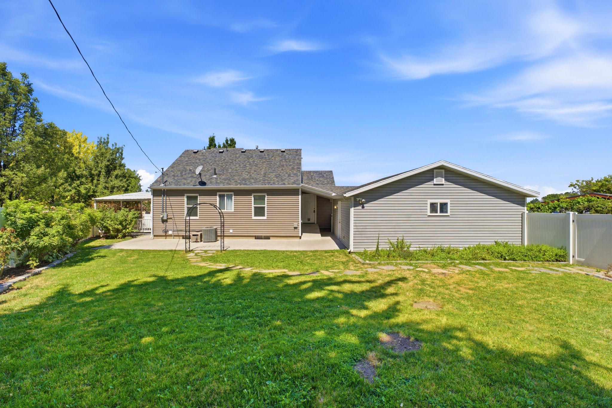 Expansive green lawn with a concrete patio and a detached auxiliary building featuring siding
