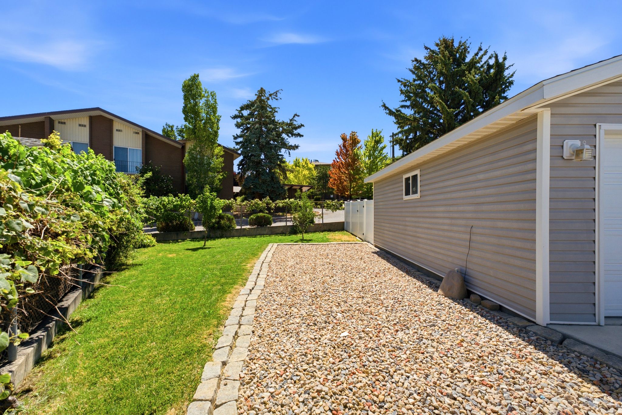 Gravel driveway with paver edging, leading to a gray vinyl-sided garage