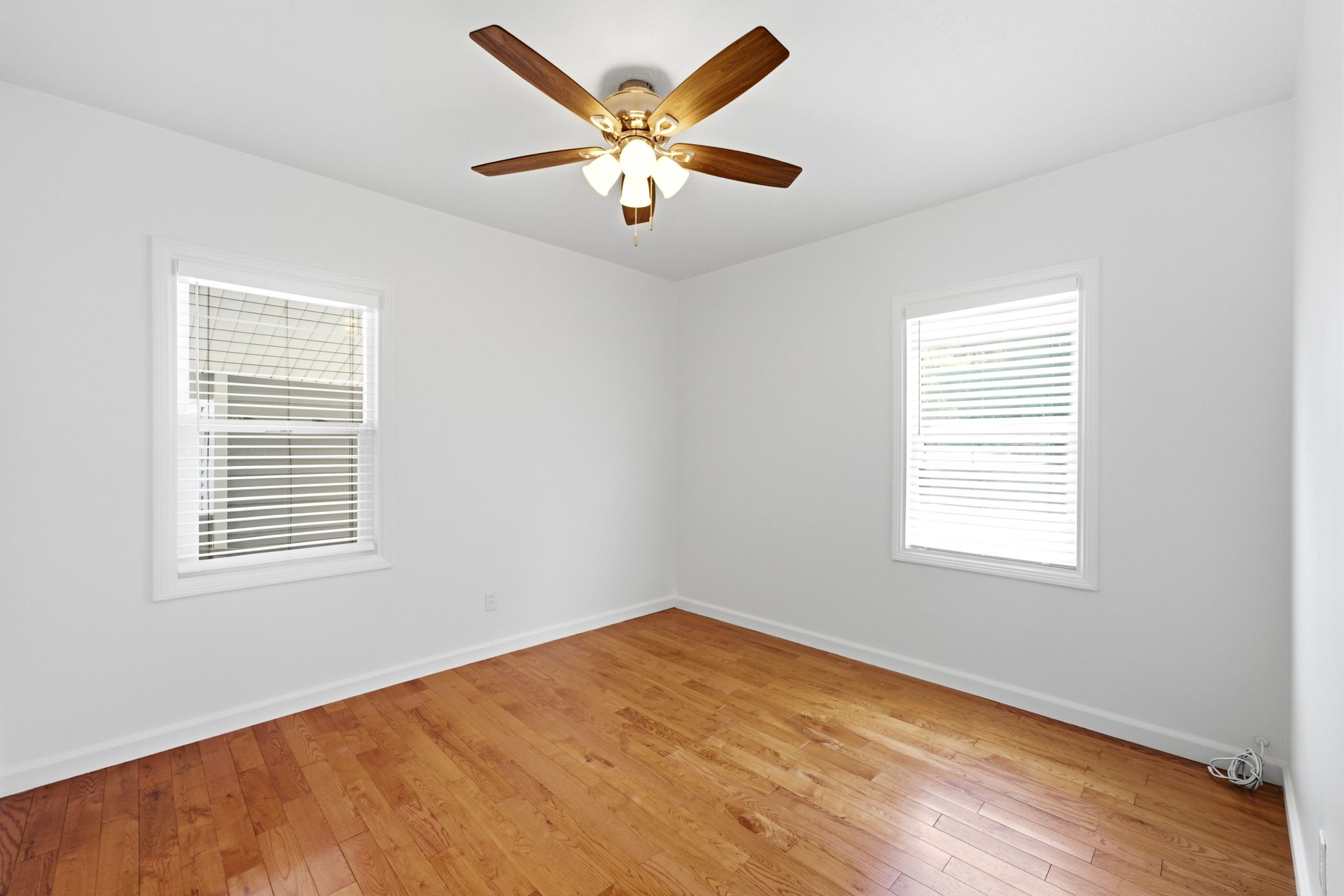 Bright interior featuring wood-finish flooring, white walls, and a ceiling fan with integrated lighting