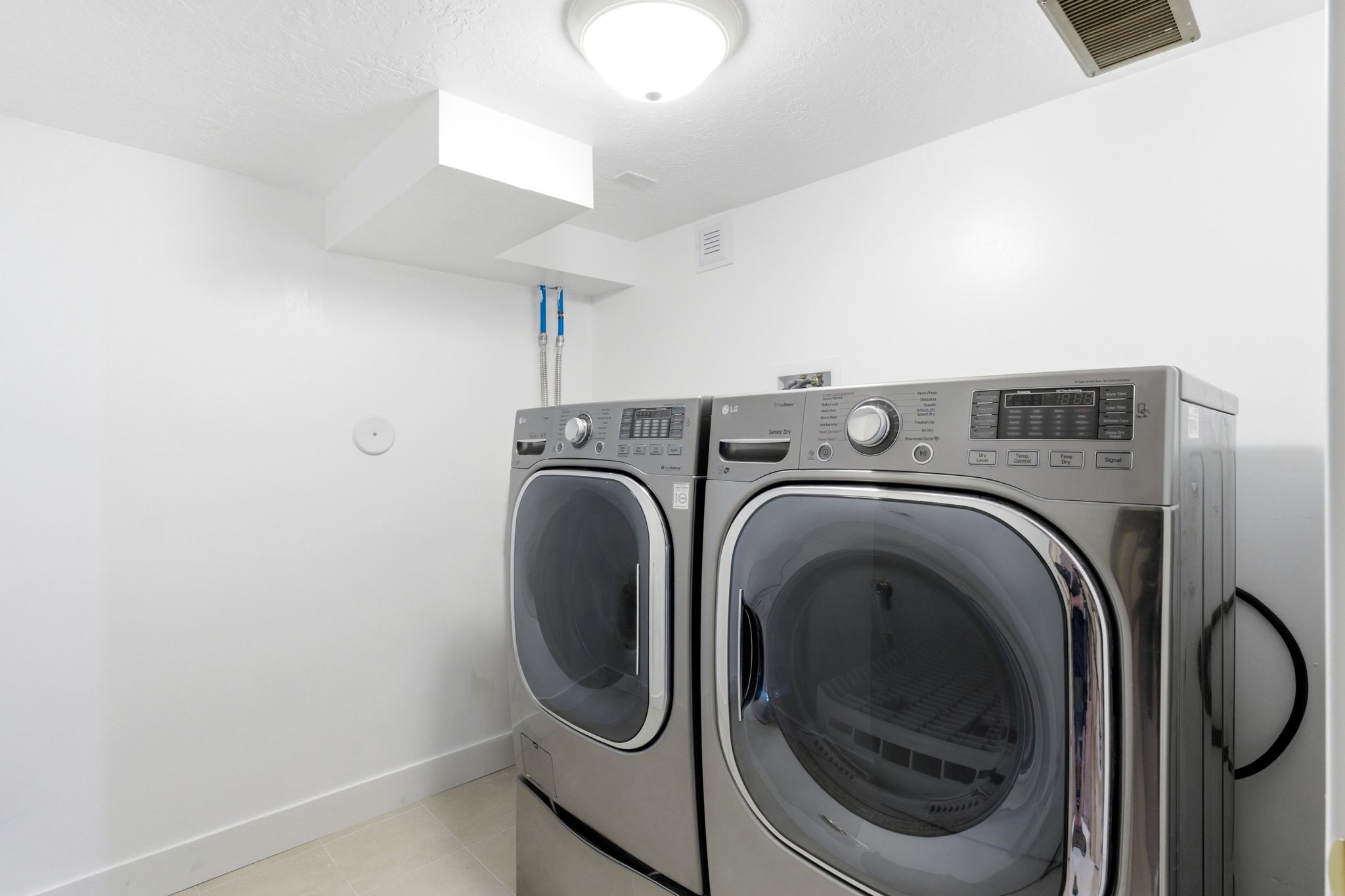 Dedicated laundry space featuring a front-loading washer and dryer, ceiling-mounted light fixture, and white painted walls