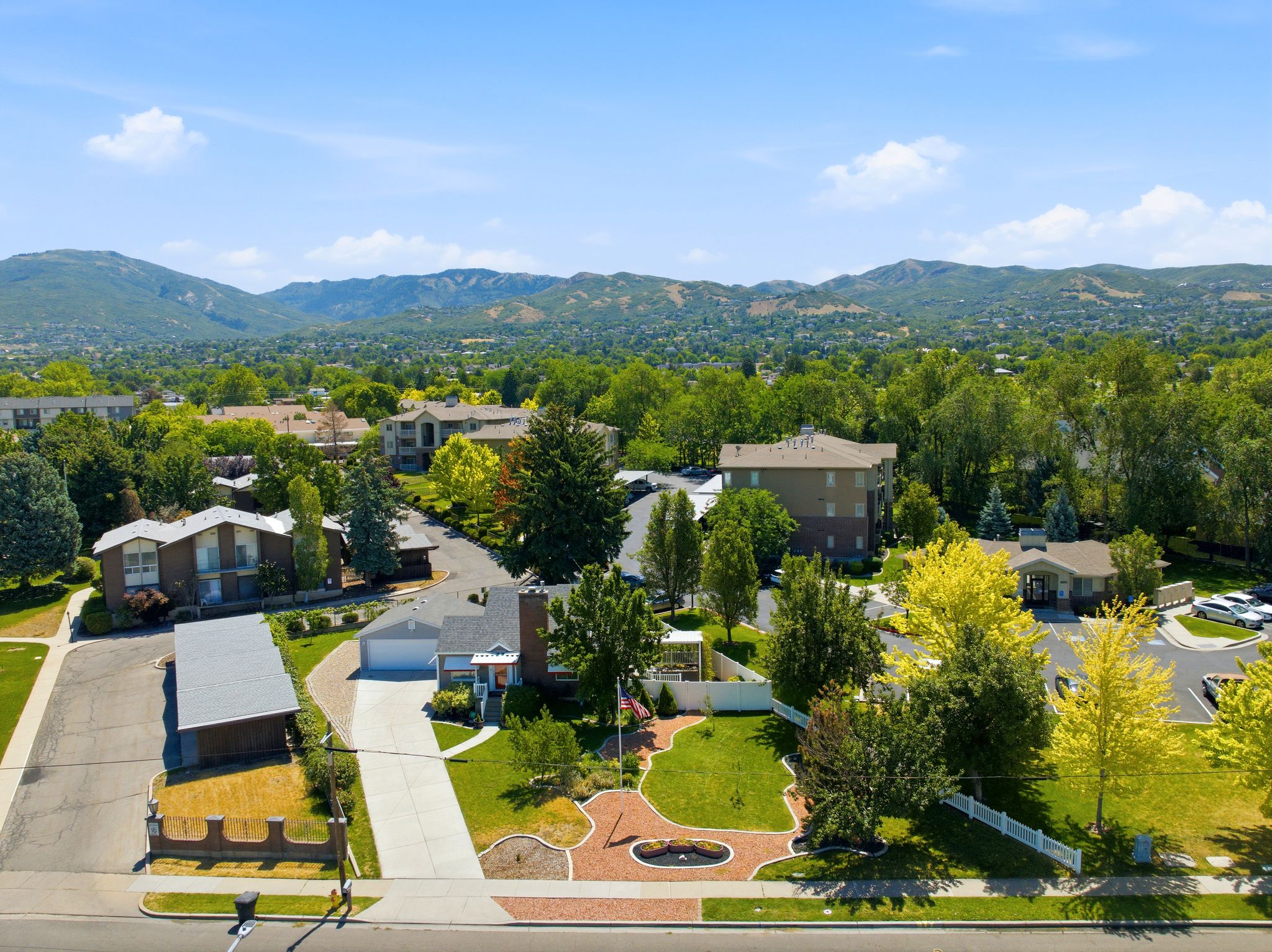 Expansive property featuring a paved driveway, a two-car garage, and a landscaped front yard with mature trees