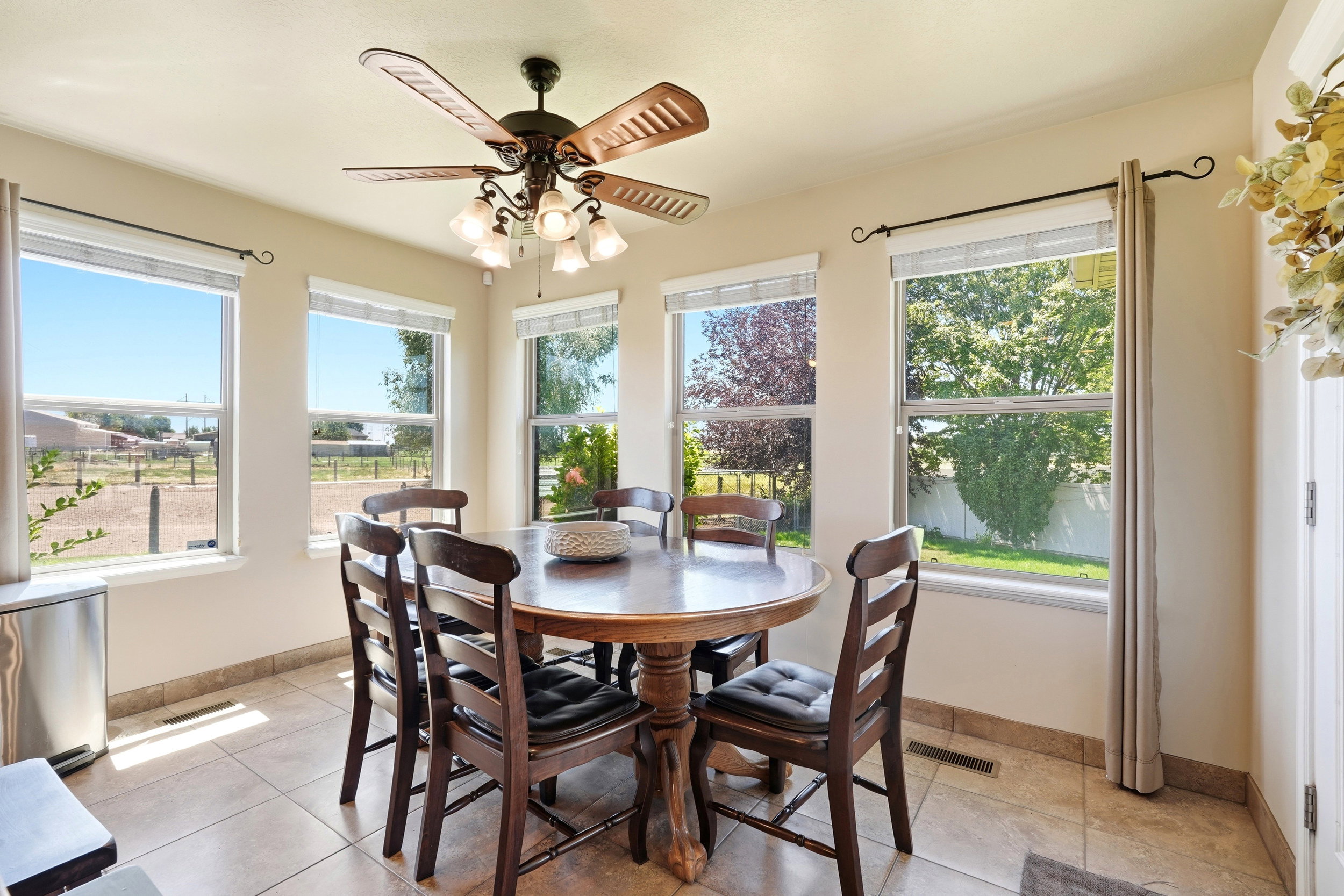 Dining area with multiple windows, tile flooring, and a ceiling fan with integrated lighting