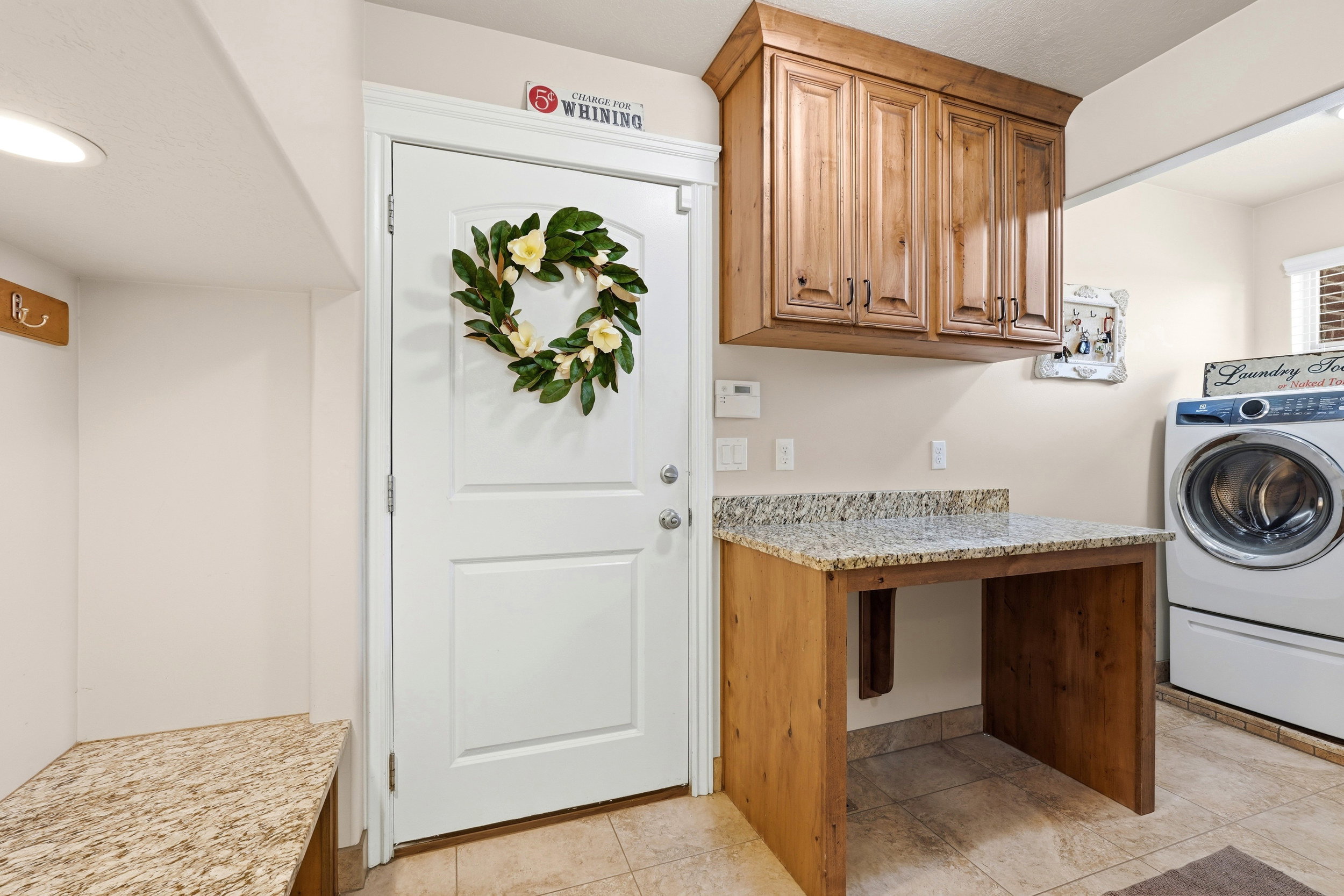 Utility room featuring wood-finish cabinetry, granite-style countertops, and ceramic tile flooring