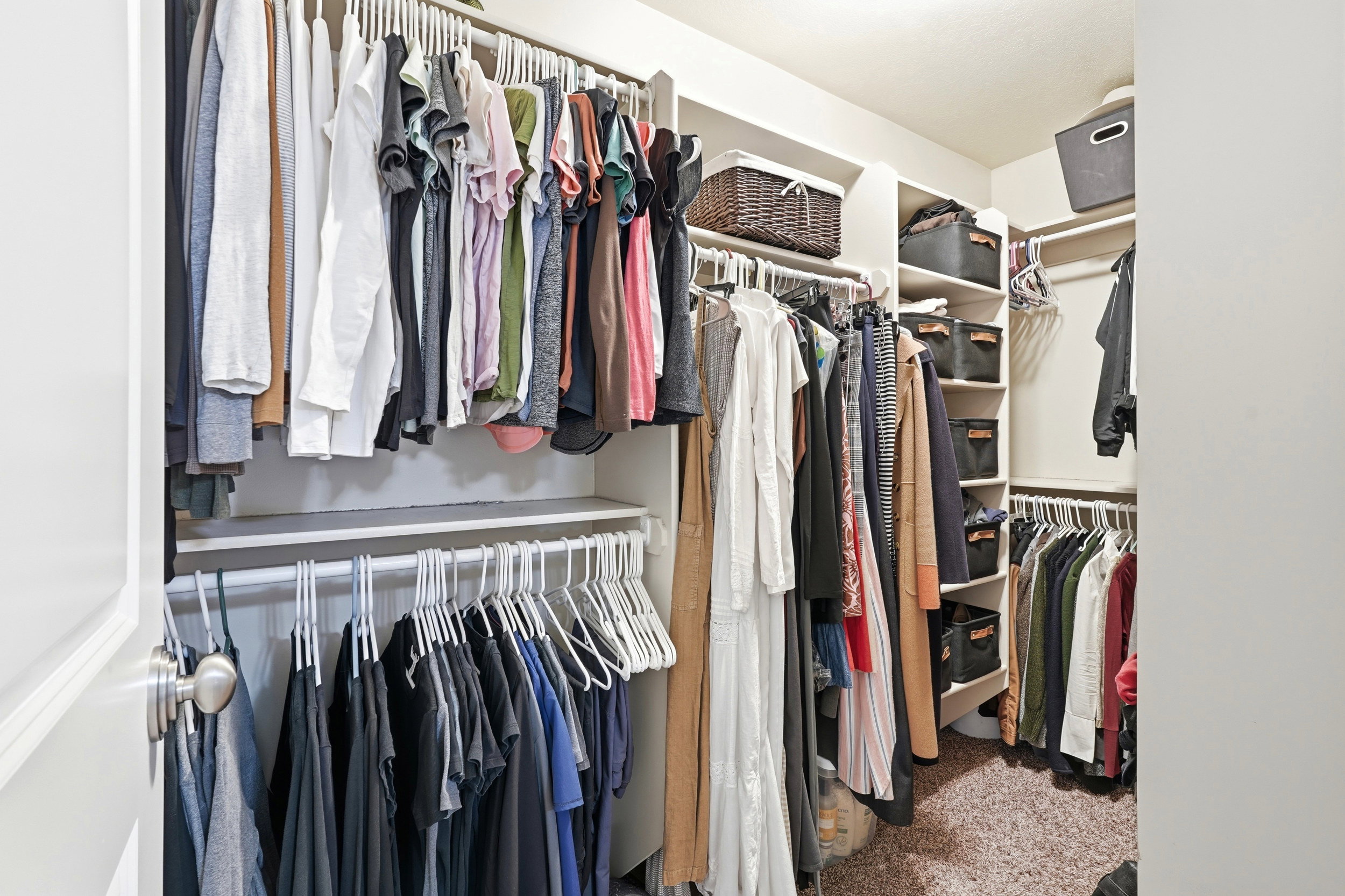 Walk-in closet featuring white built-in shelving, multiple hanging rods, and an L-shaped configuration