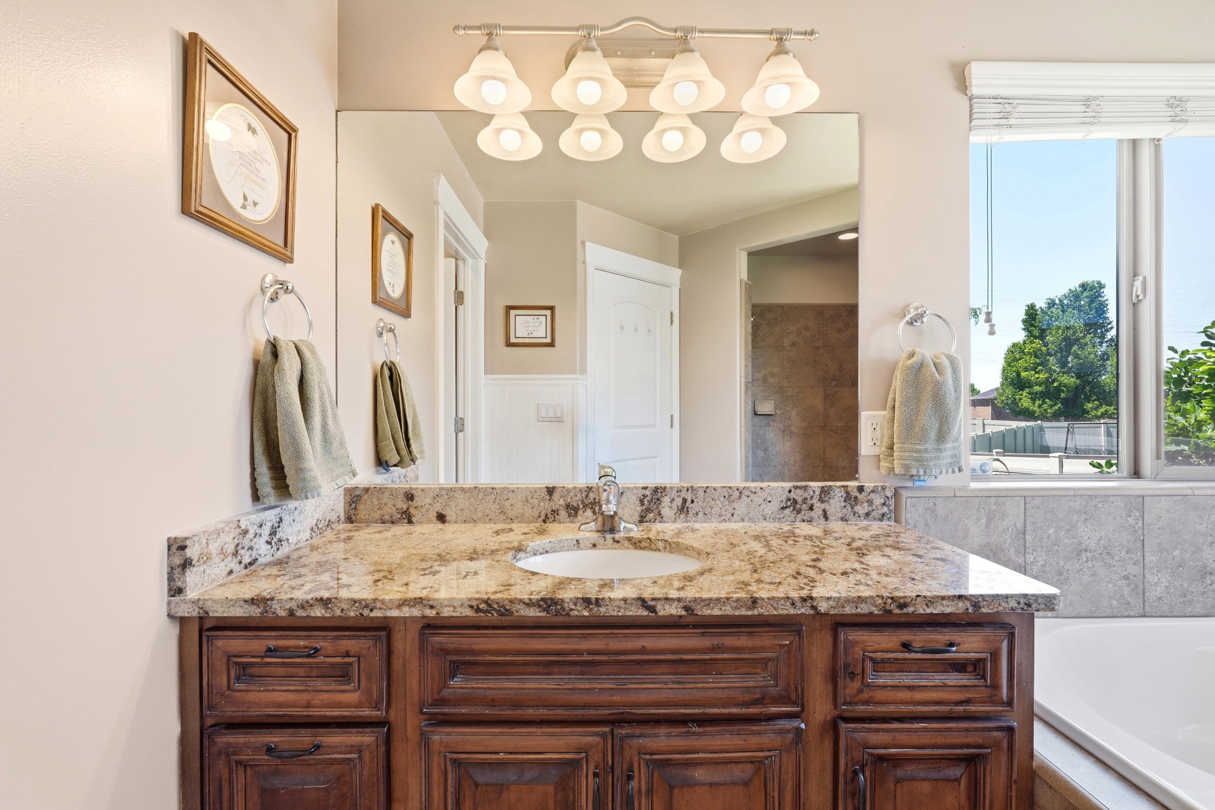Elegant vanity featuring a single basin set into a granite-finish countertop, complemented by dark wood cabinetry