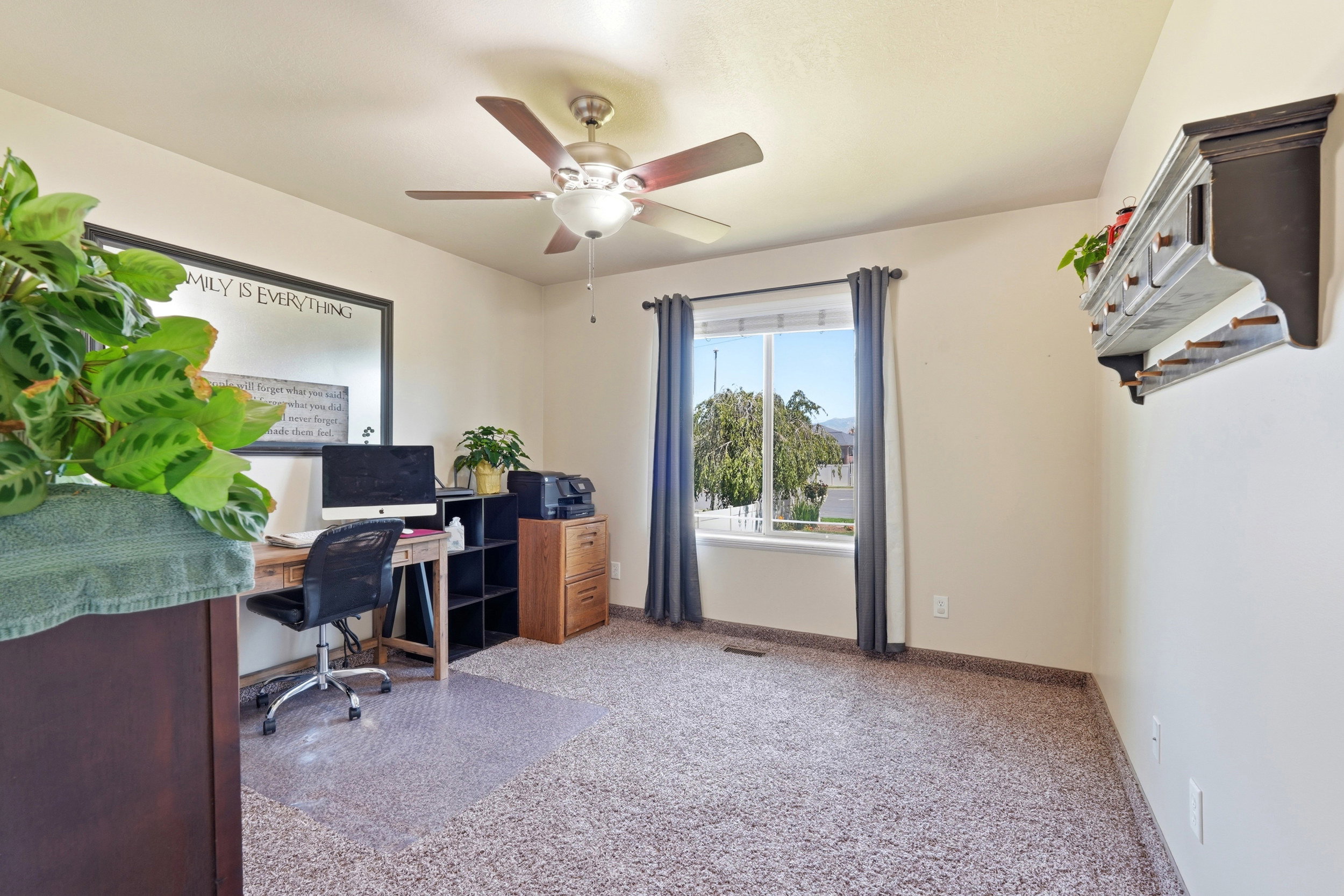 Bright room featuring a window with exterior views, light neutral wall paint, and a ceiling fan with integrated lighting