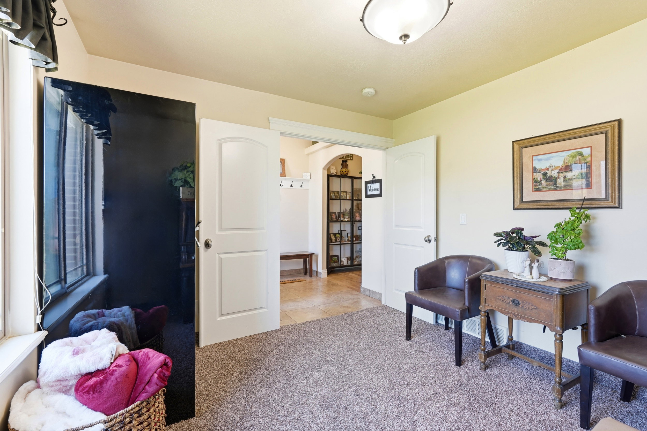 Carpeted room featuring a white window frame, an interior door with an arched top panel, and a ceiling-mounted light fixture