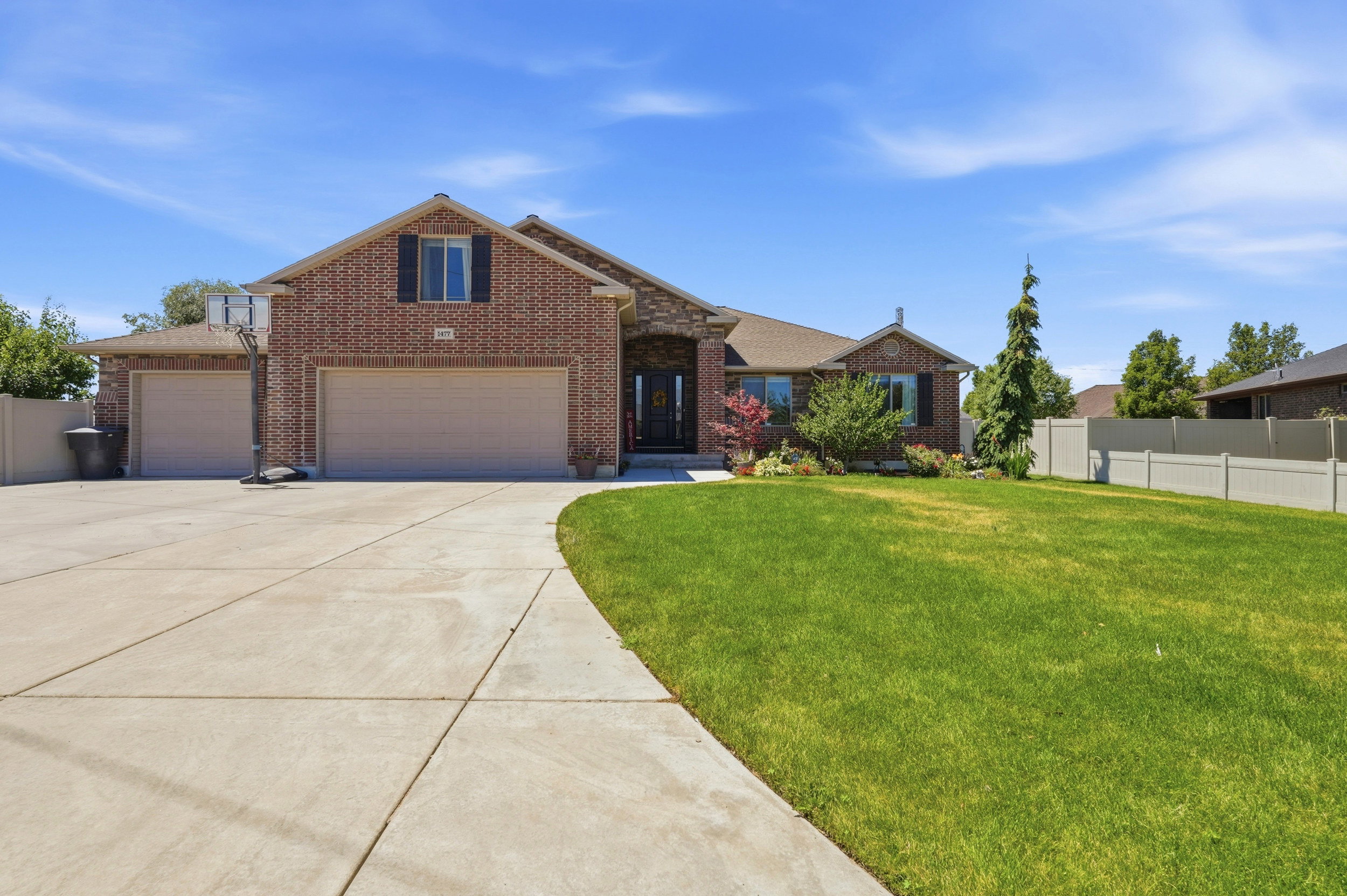 Brick exterior residence featuring a multi-gable roofline and a substantial concrete driveway