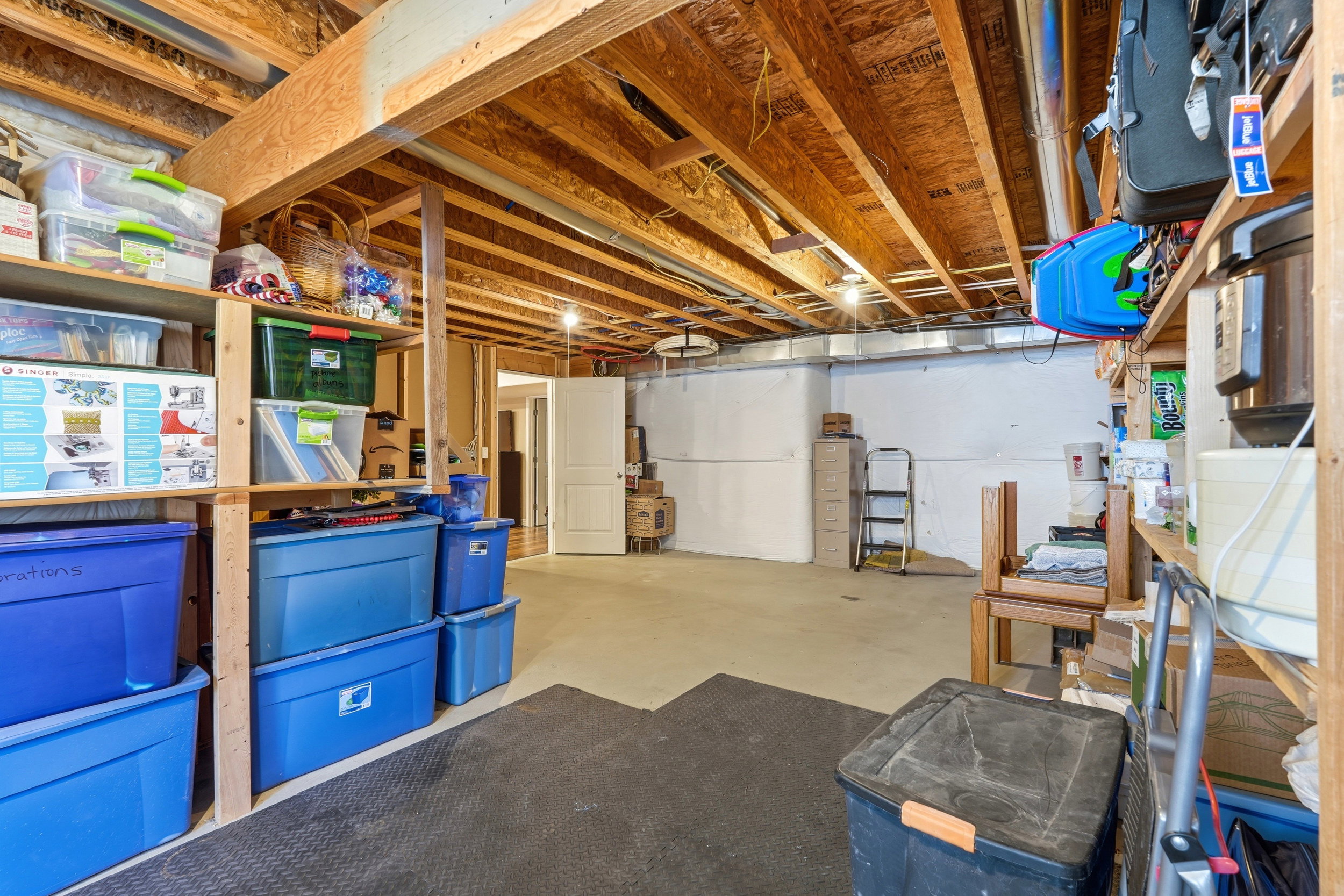 Unfinished basement featuring exposed wood ceiling joists and concrete flooring