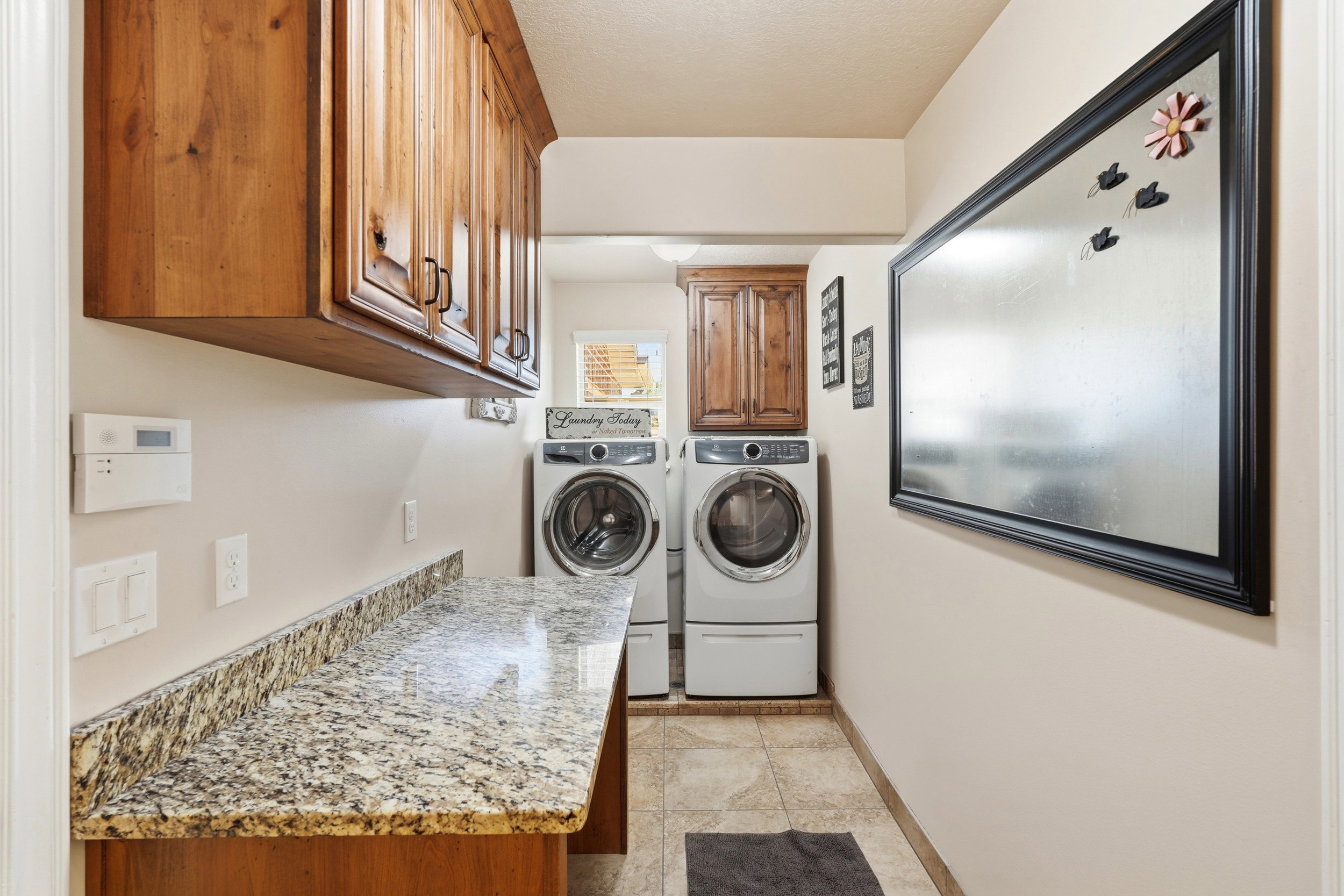 Functional utility space featuring wood cabinetry, a light-toned patterned countertop, and tile flooring