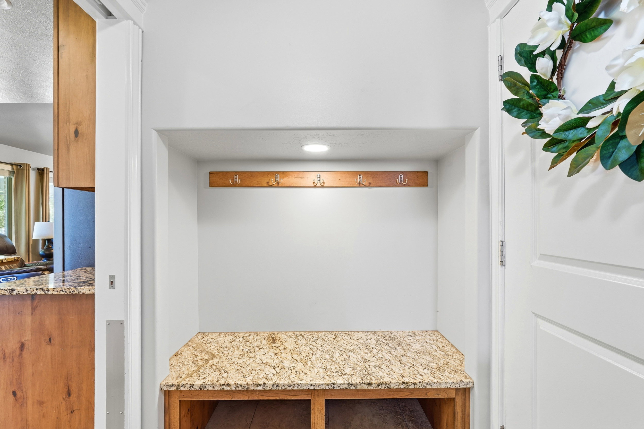 Built-in entryway bench with a light-toned granite countertop, under-bench shelving, and a wall-mounted coat rack