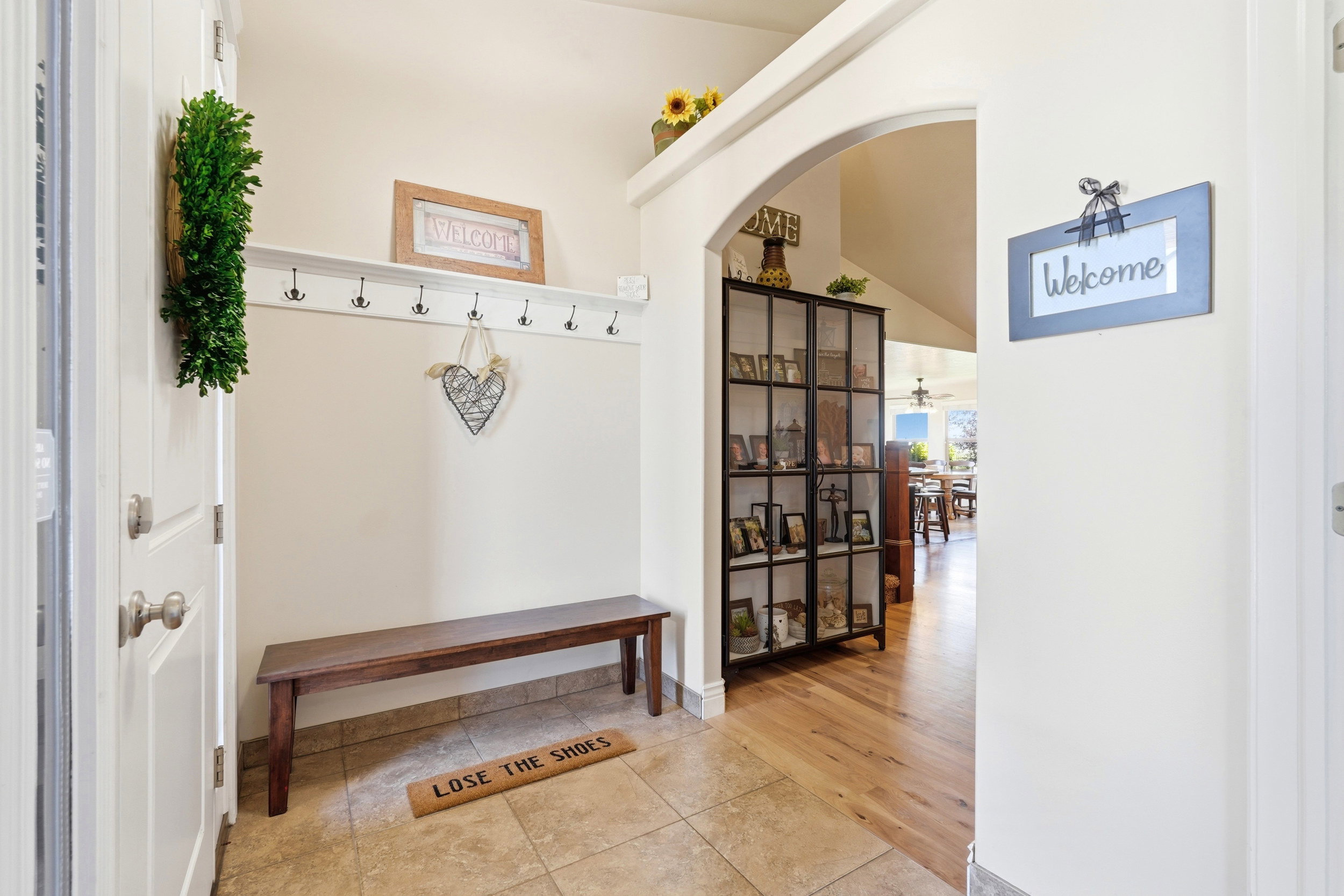 Entryway featuring tile flooring, a built-in coat rack with shelving, and an arched architectural opening