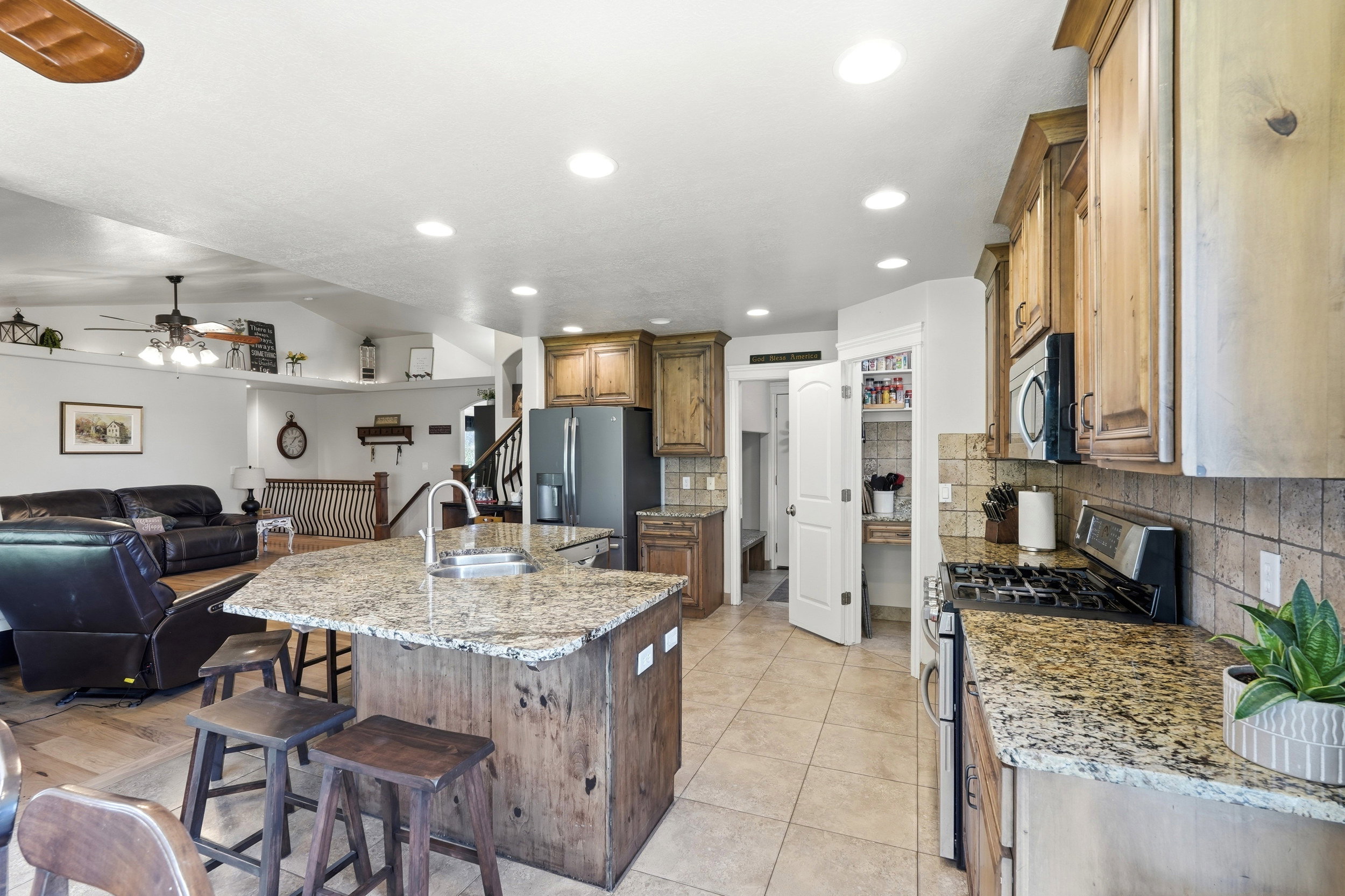 Kitchen featuring granite countertops, wood cabinetry, stainless steel appliances, a gas range, and a built-in pantry