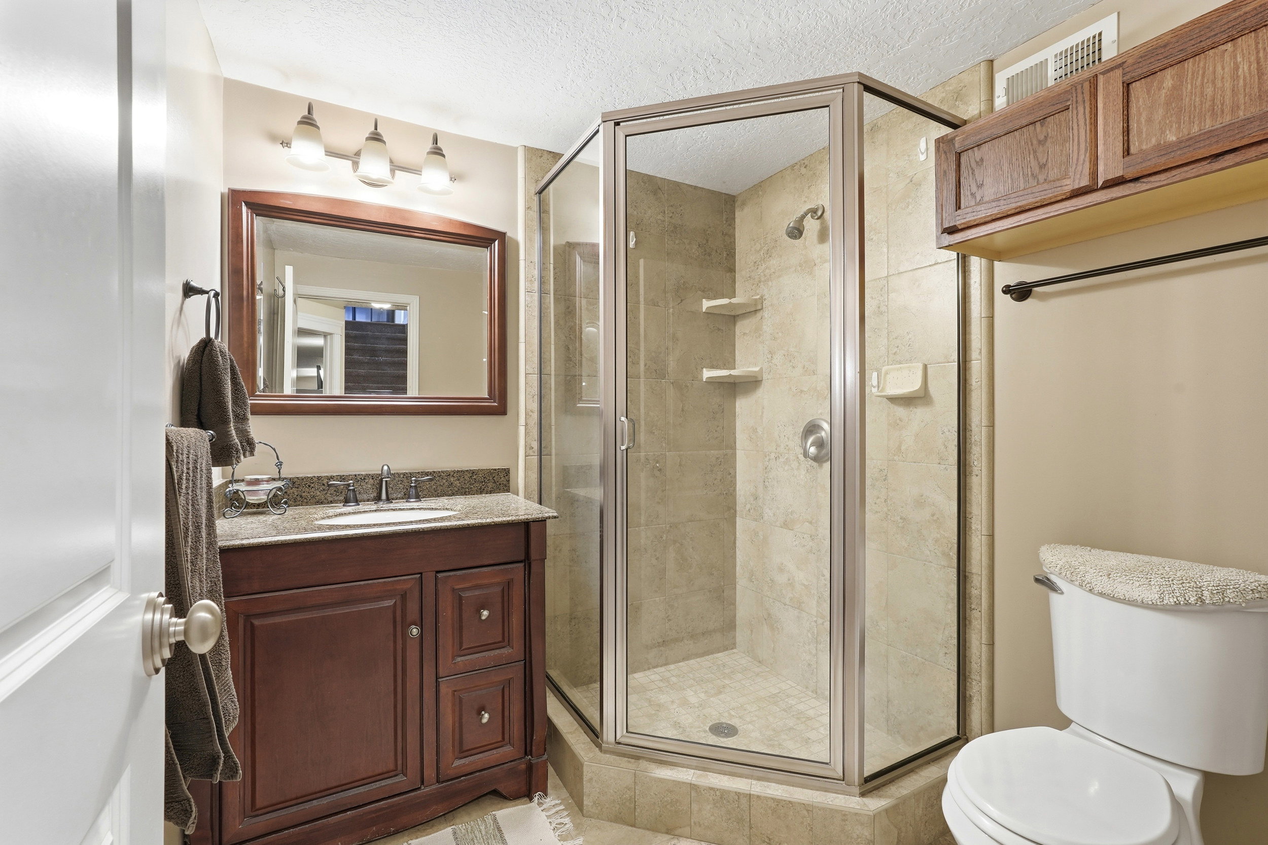 Bathroom featuring a dark wood vanity with a granite-style countertop, undermount sink, and framed mirror