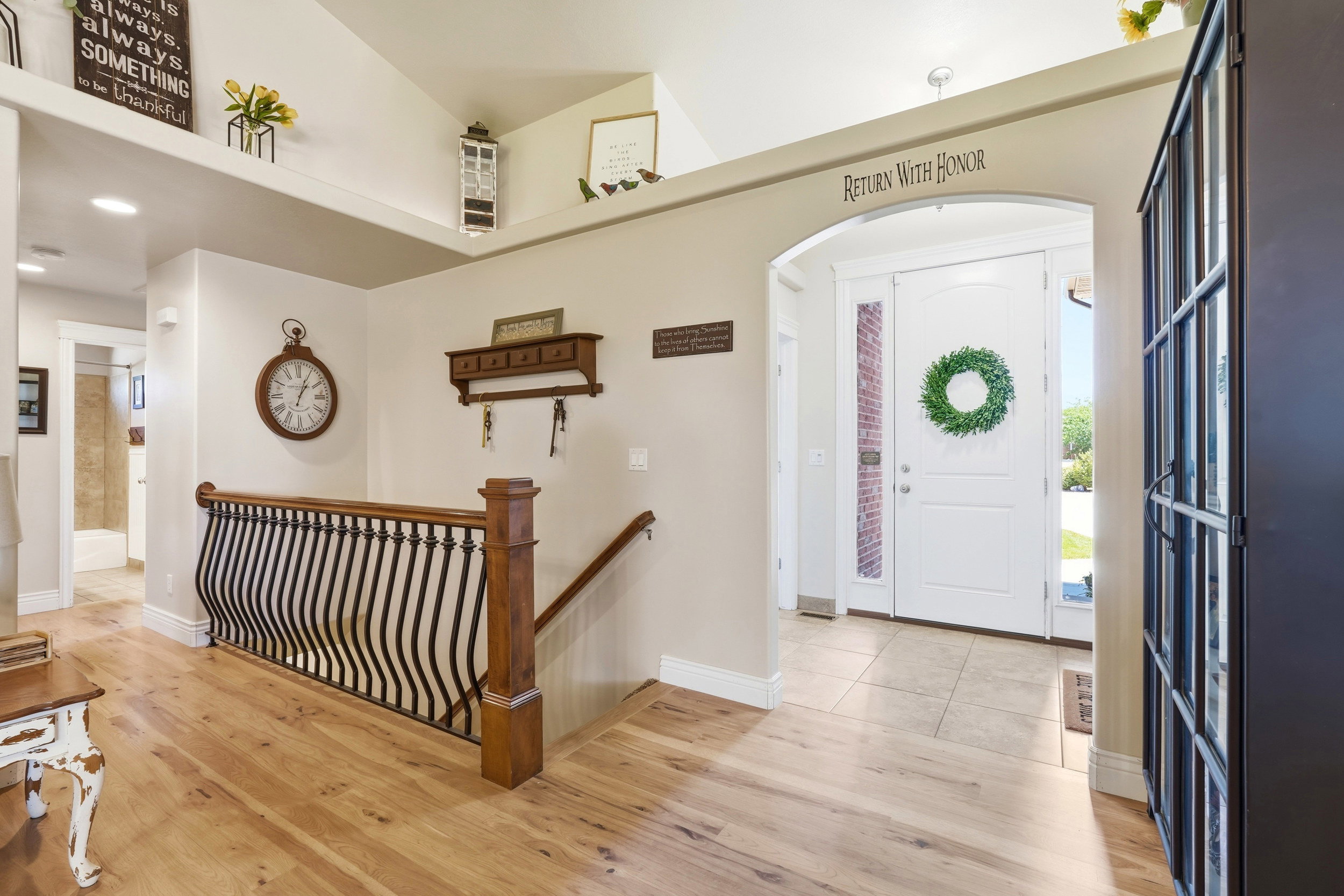 Entryway featuring a white paneled door with sidelights, an arched doorway, and tile flooring