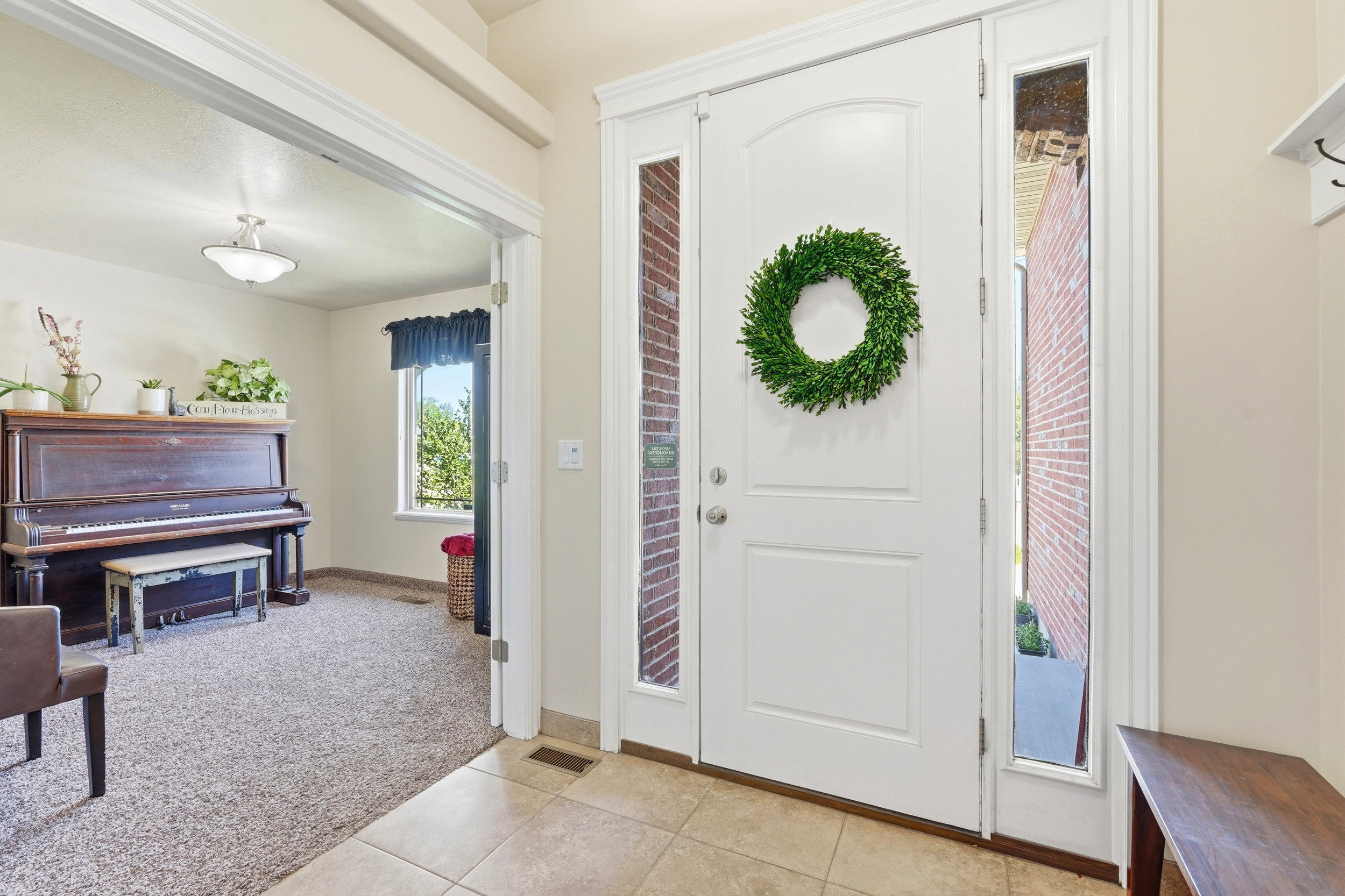 Entryway with tiled flooring and a white front door featuring an arched panel and sidelights