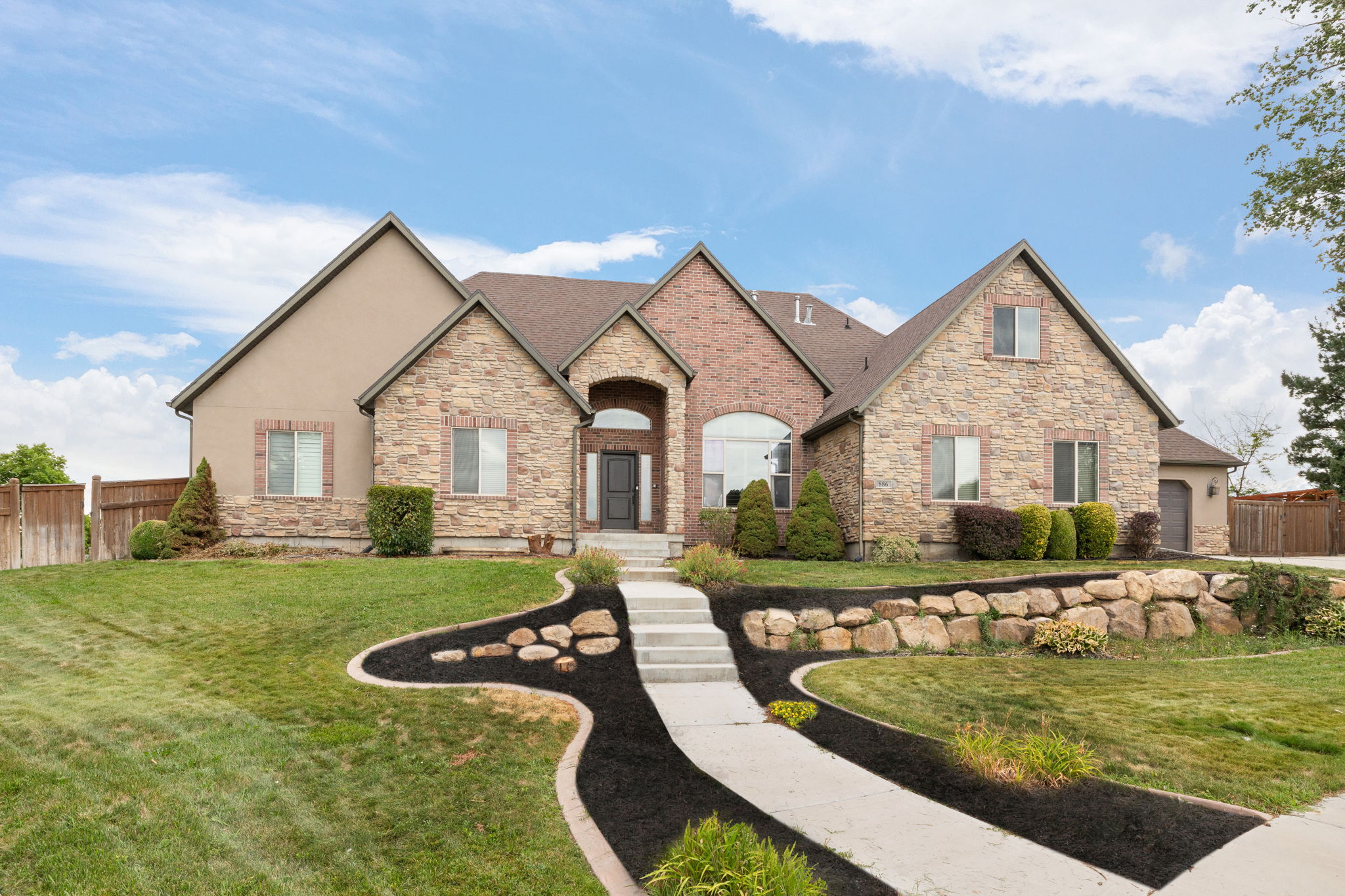 Stately residence featuring a stone and brick facade, arched entryway, and a multi-level roofline