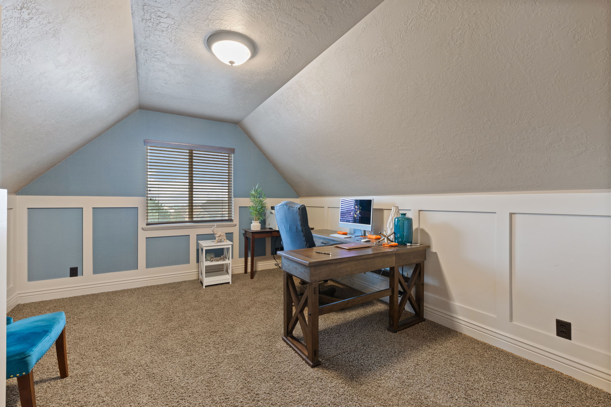 Carpeted room with sloped ceilings, featuring a built-in window and wainscoting