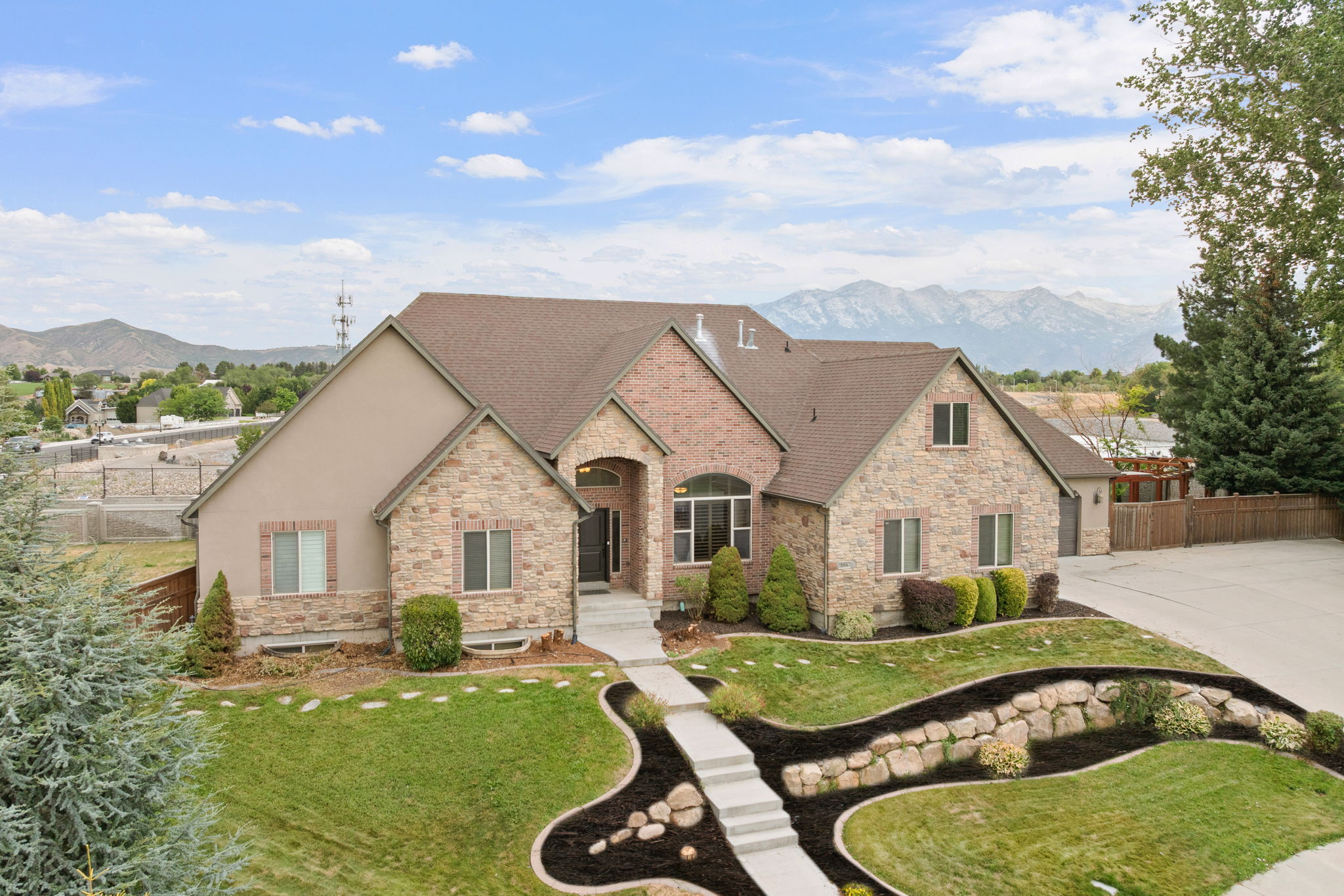 Multi-level home featuring a stone and stucco exterior, arched entry, and a paved driveway