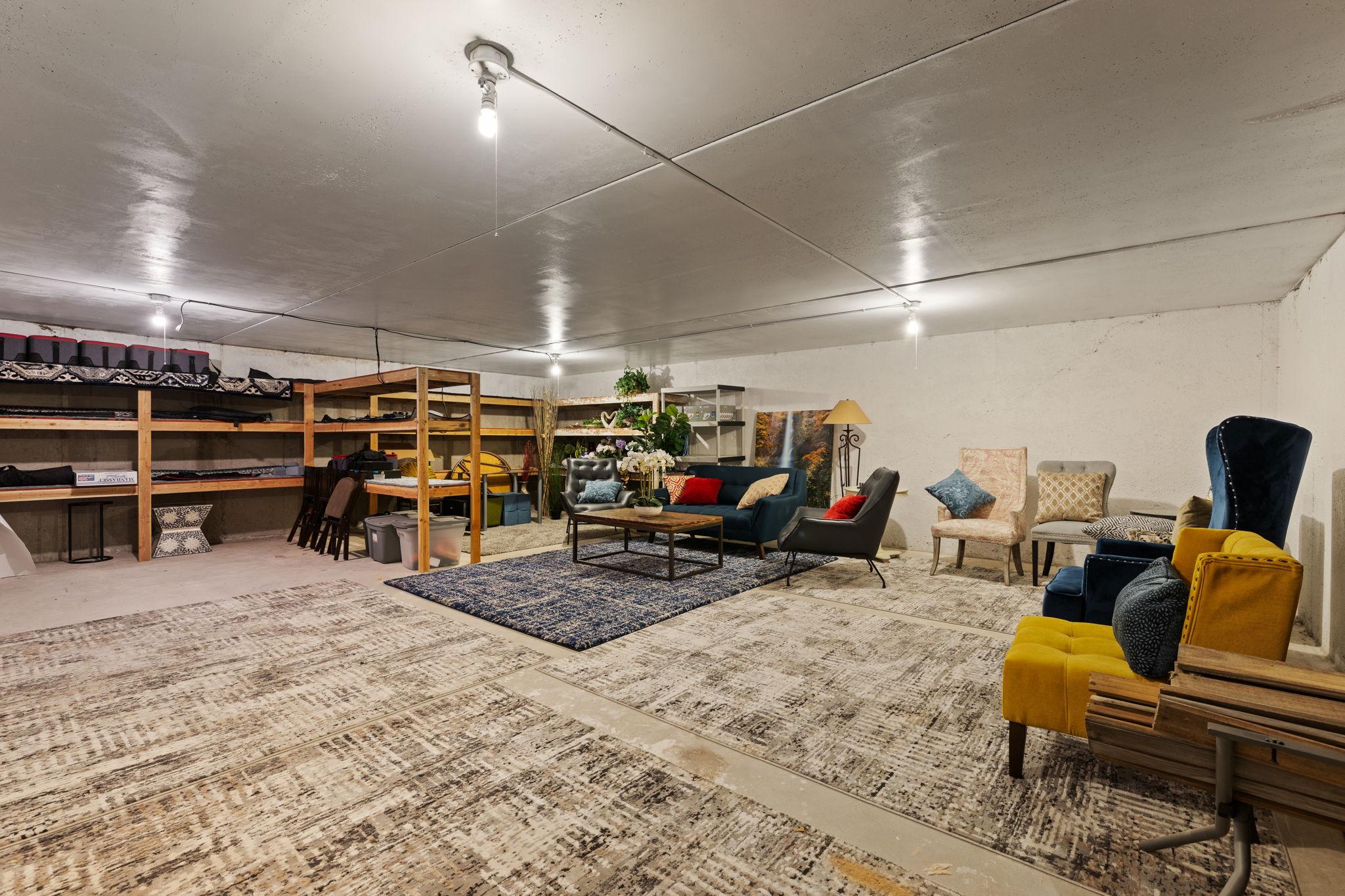 Versatile lower-level space featuring a concrete floor, exposed conduit lighting, and painted concrete walls