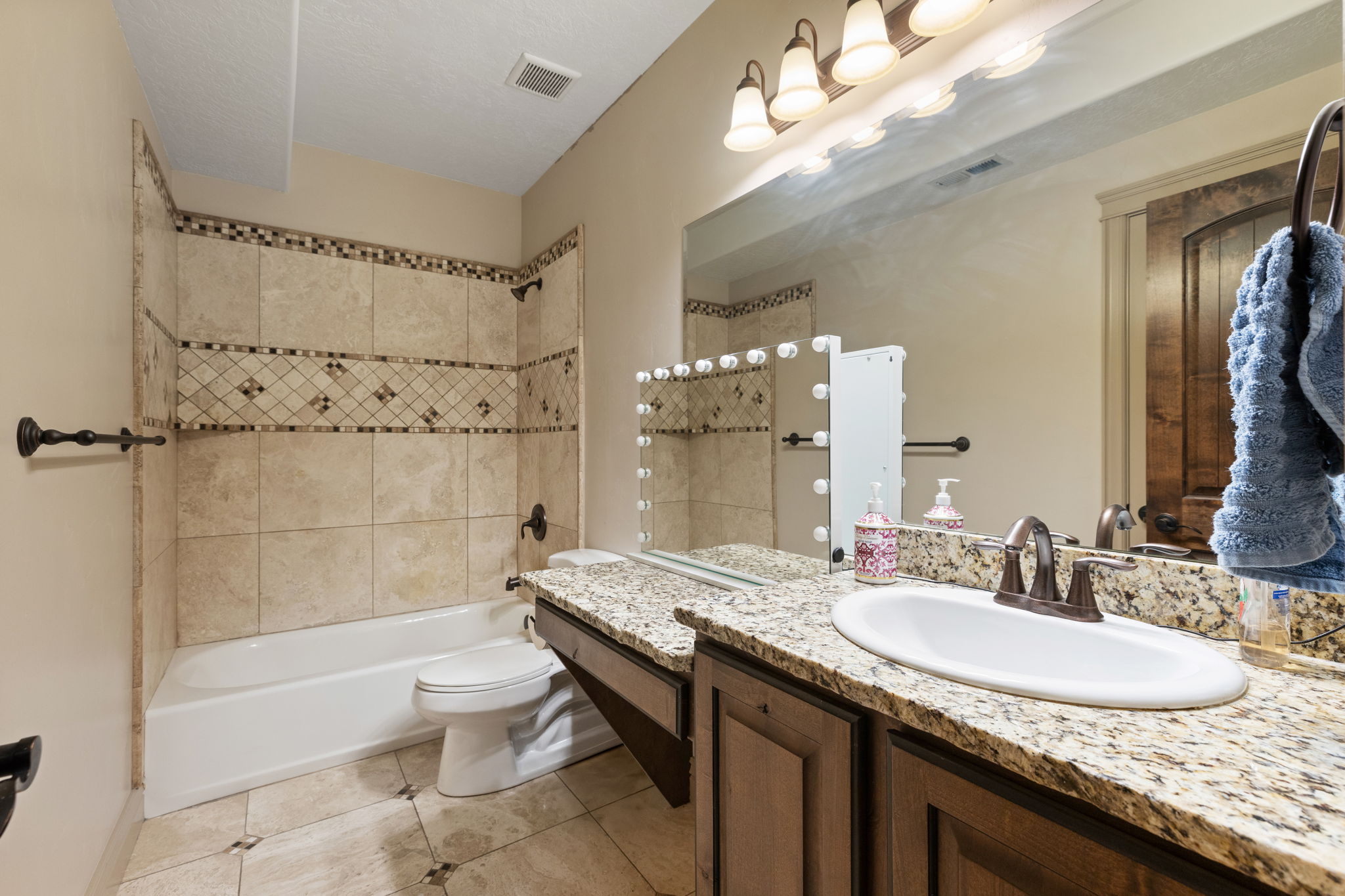 Bathroom featuring a large vanity with an oval undermount sink, a mottled stone countertop, and wood-finish cabinetry
