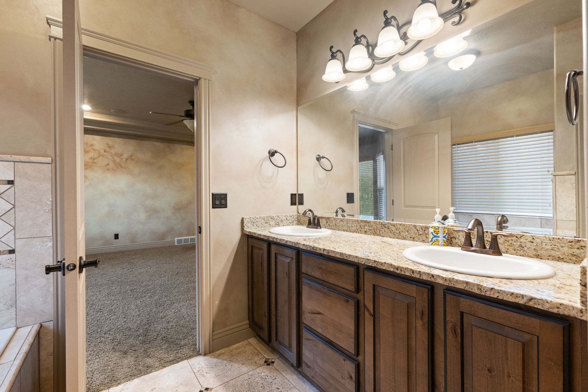 Double vanity featuring granite countertops, undermount sinks with bronze-finish faucets, and wood cabinetry