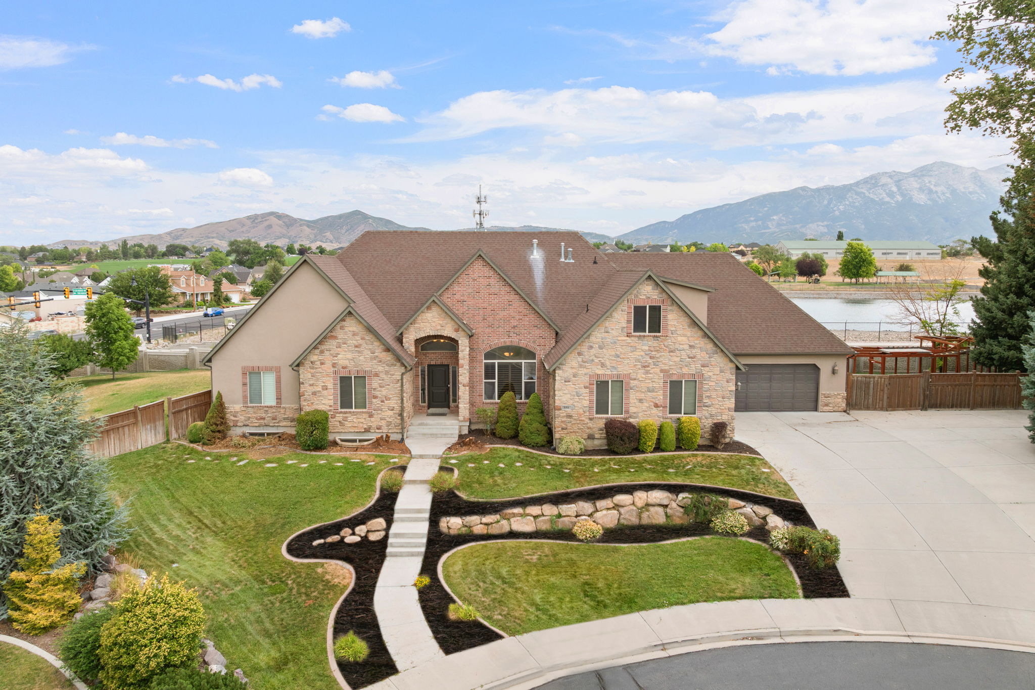 Stately residence featuring a stone and brick facade, a multi-car driveway, and an attached two-car garage