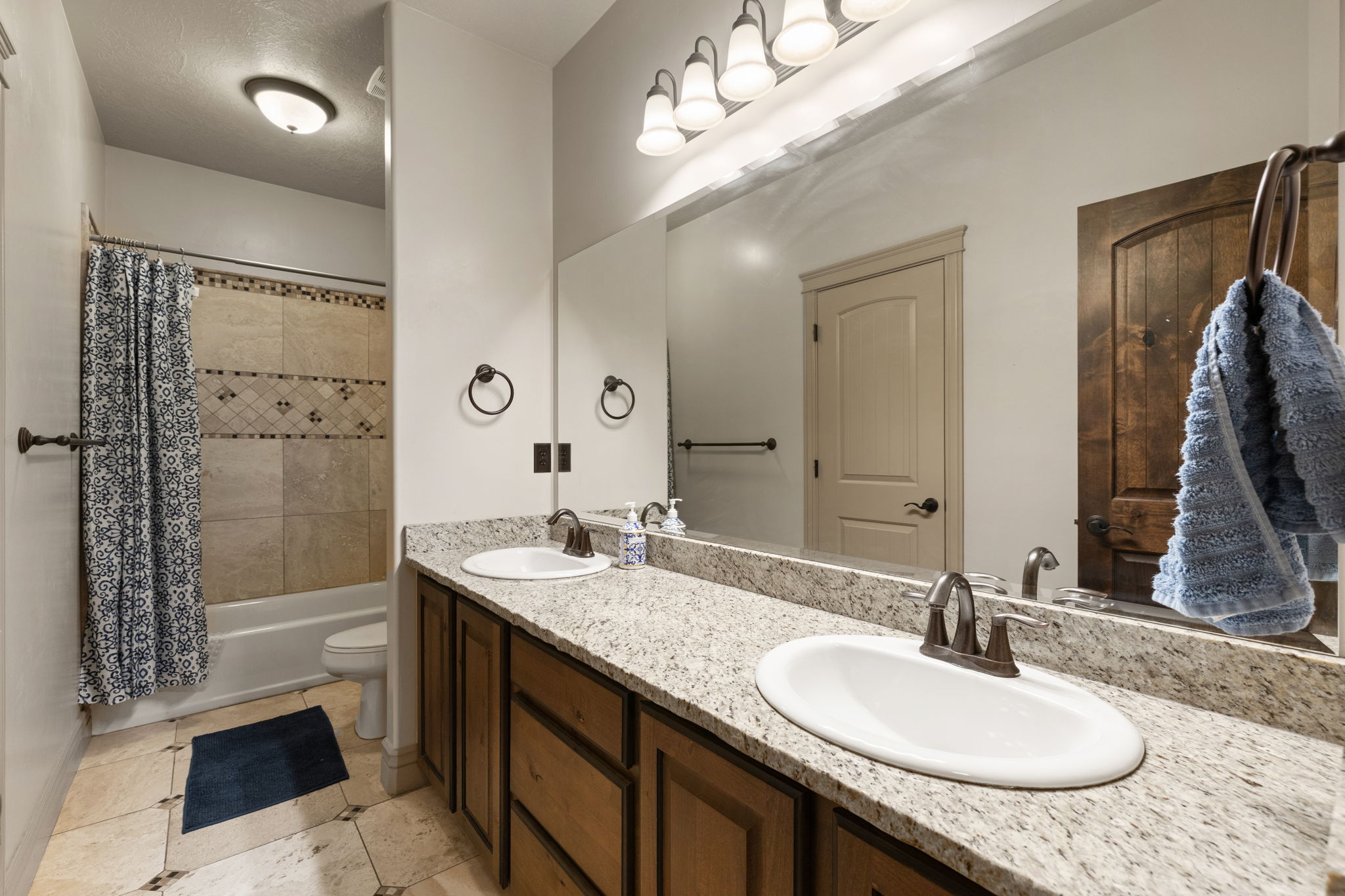 Double vanity with granite-style countertop, undermount sinks, and bronze-finish fixtures